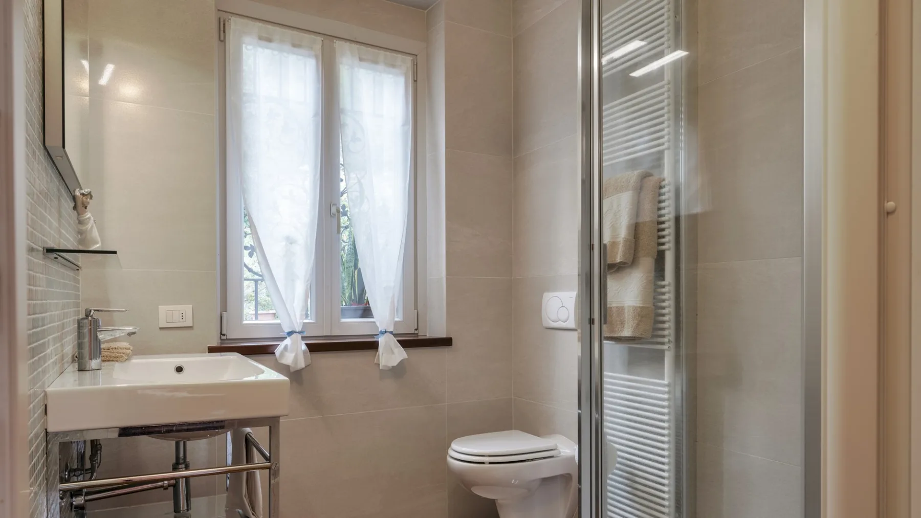 A tiled bathroom with a sink, toilet, and glass shower enclosure.