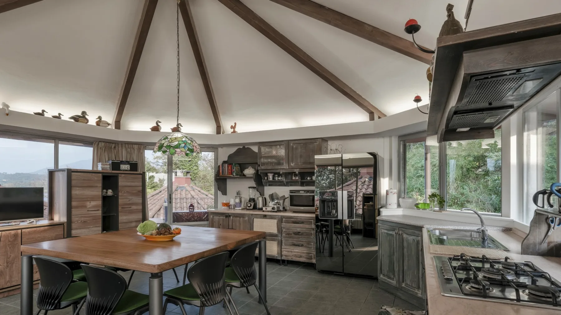 A spacious kitchen and dining area with a large wooden table and exposed ceiling beams.