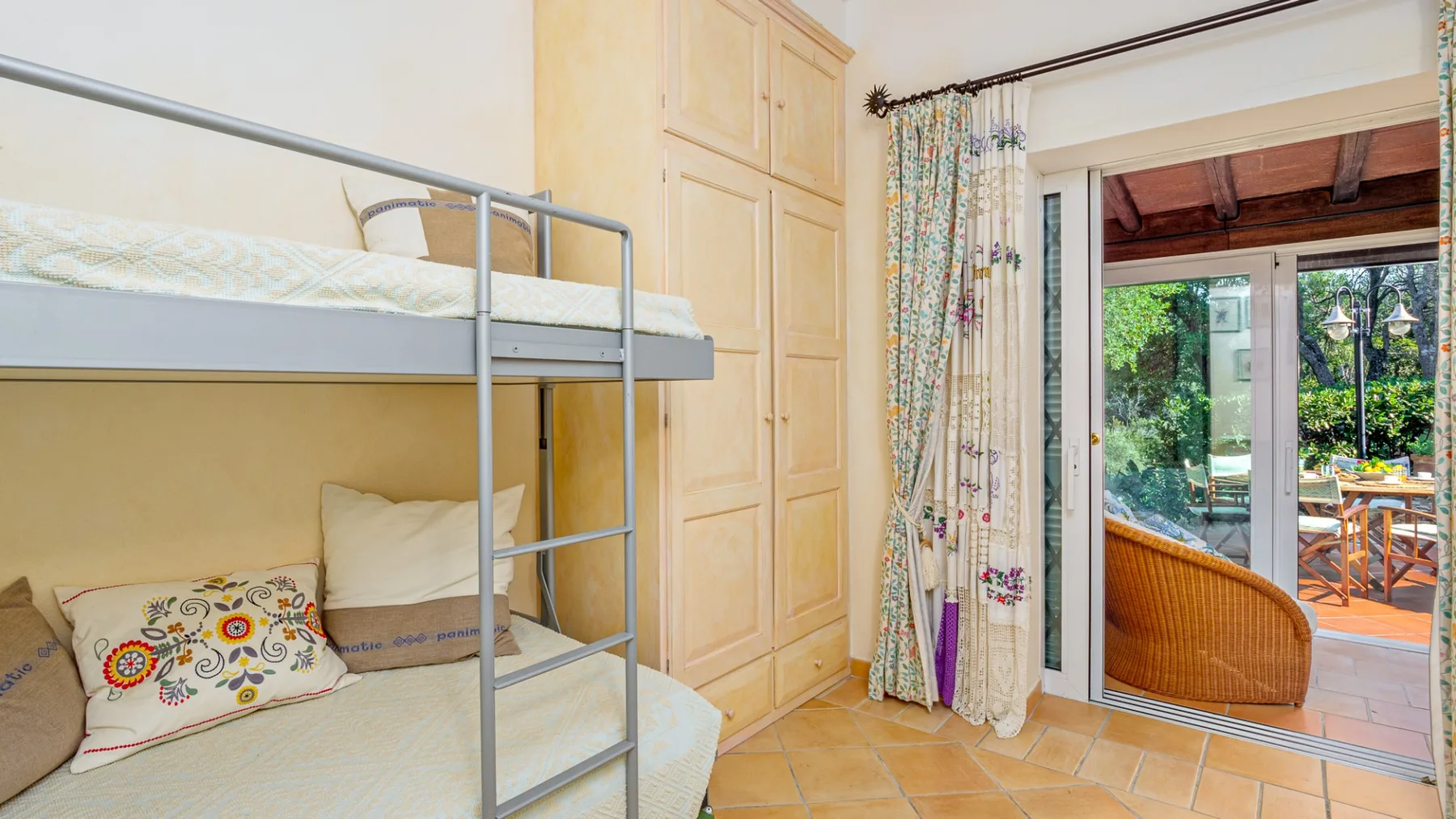 Un dormitorio con una litera junto a un armario y puertas de vidrio que dan a un patio.
