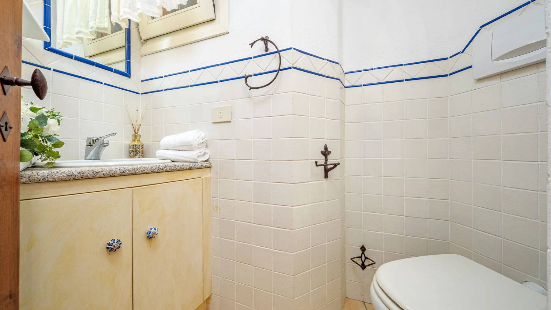 Un baño con azulejos, un lavabo con mueble y un inodoro.