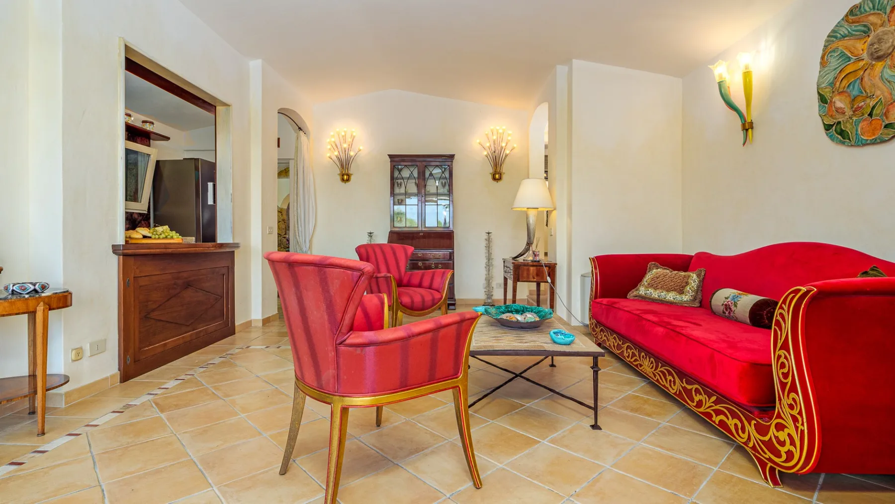 Una sala de estar luminosa con asientos rojos y una mesa de centro con tapa de vidrio.