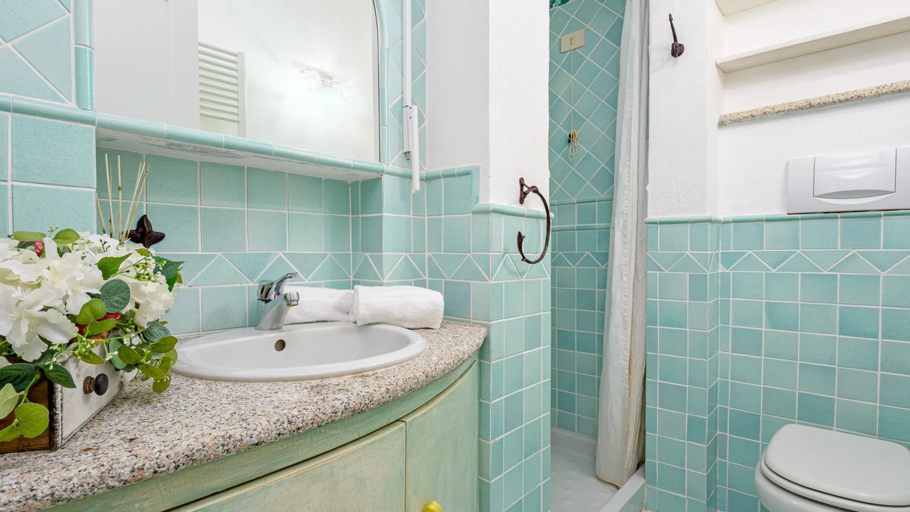 Un baño con azulejos, lavabo, ducha e inodoro.
