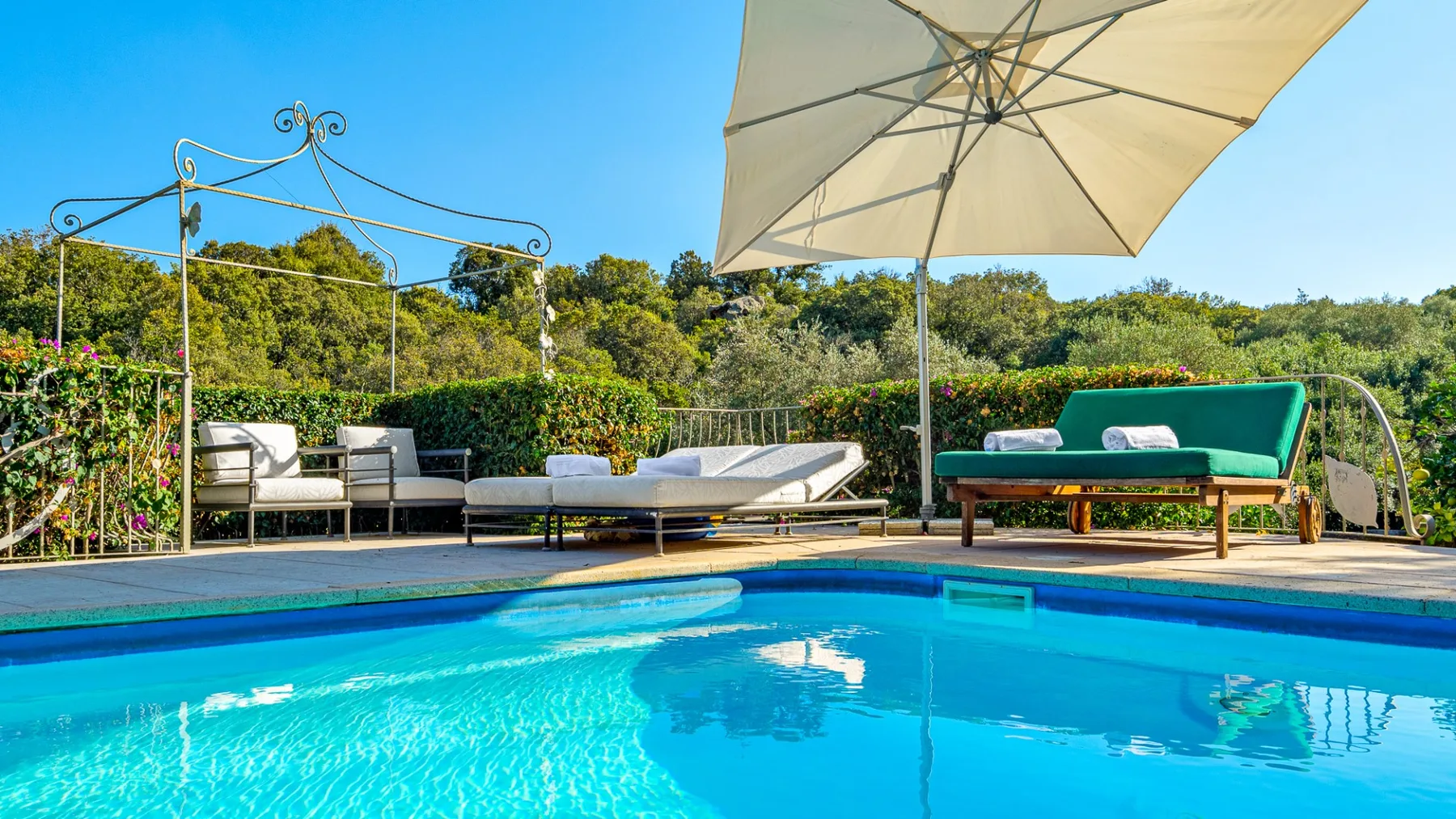 Una piscina al aire libre con asientos de descanso y una sombrilla grande.
