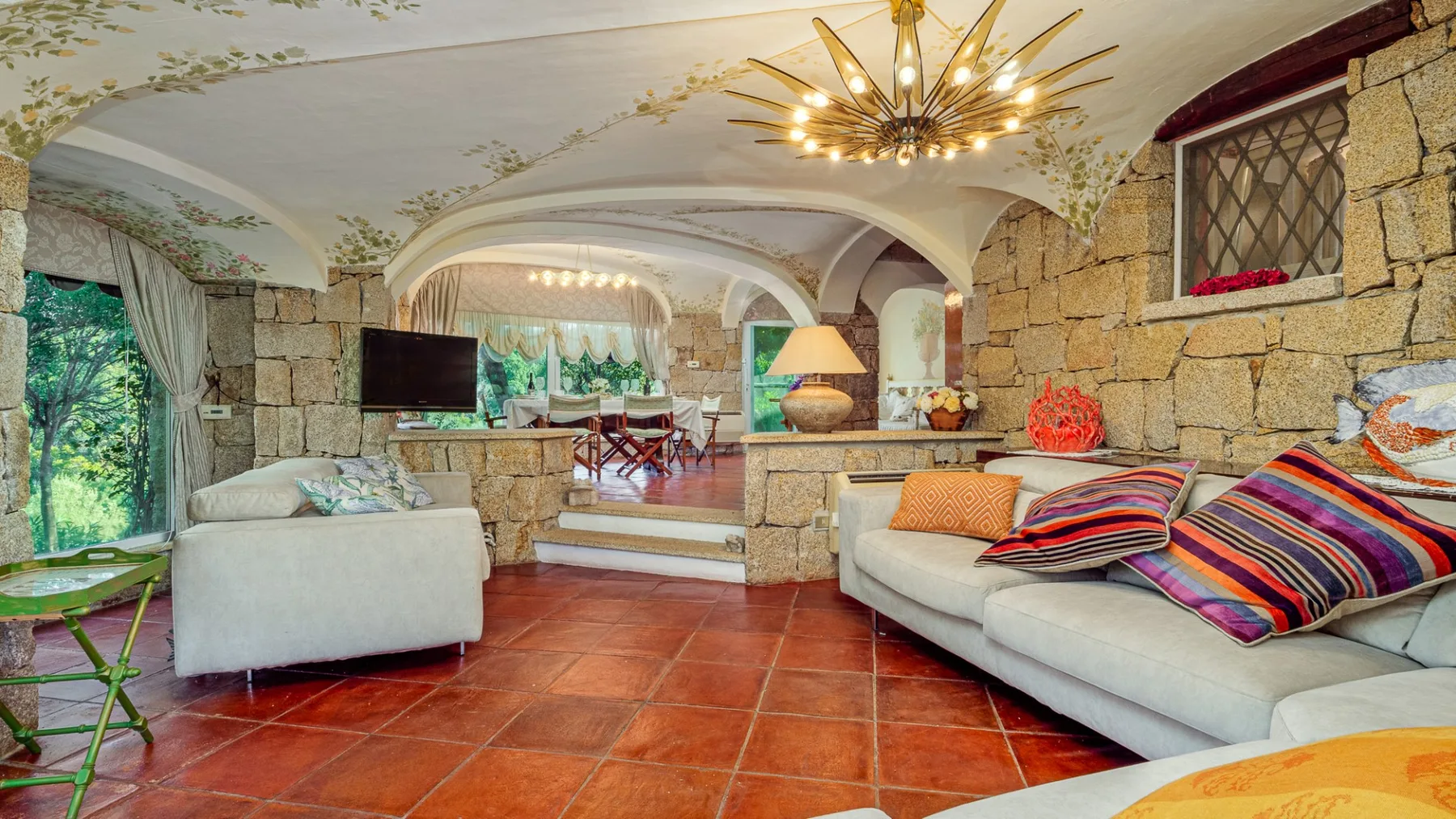 Una sala de estar con asientos, una pared de piedra y un comedor contiguo.