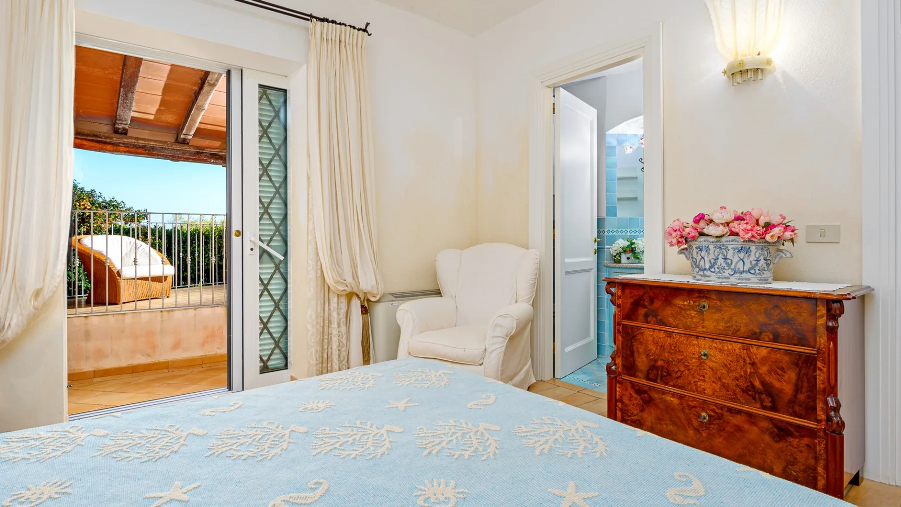 Un dormitorio con una cama, un sillón y una cómoda de madera.