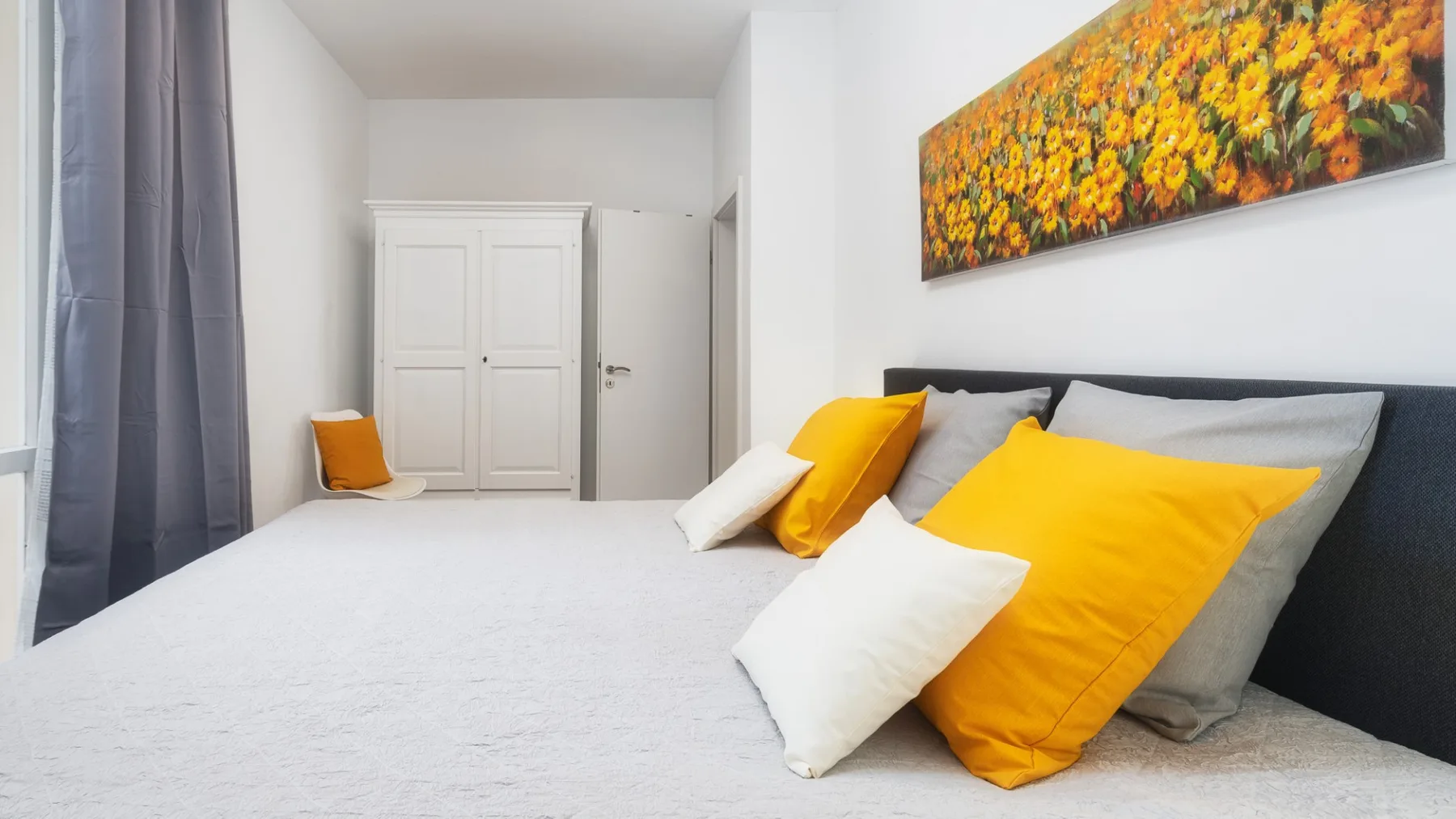 Un dormitorio con una cama vestida con ropa de cama blanca y amarilla.