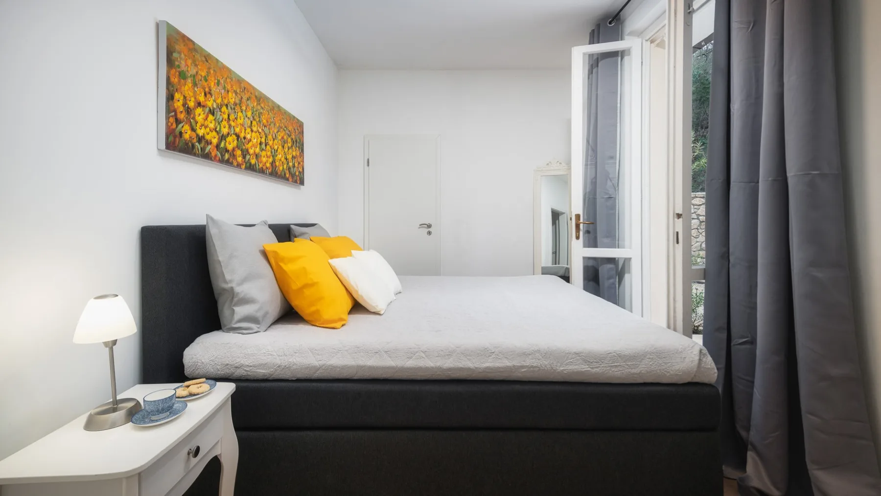 Un dormitorio con una cama arreglada y almohadas de colores junto a una puerta de vidrio.