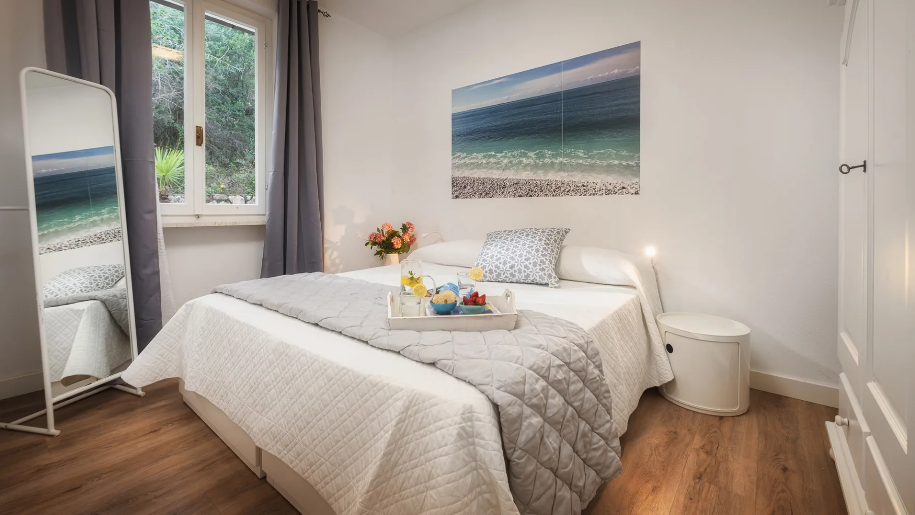 Un dormitorio con una cama bien tendida y una gran fotografía de playa en la pared.