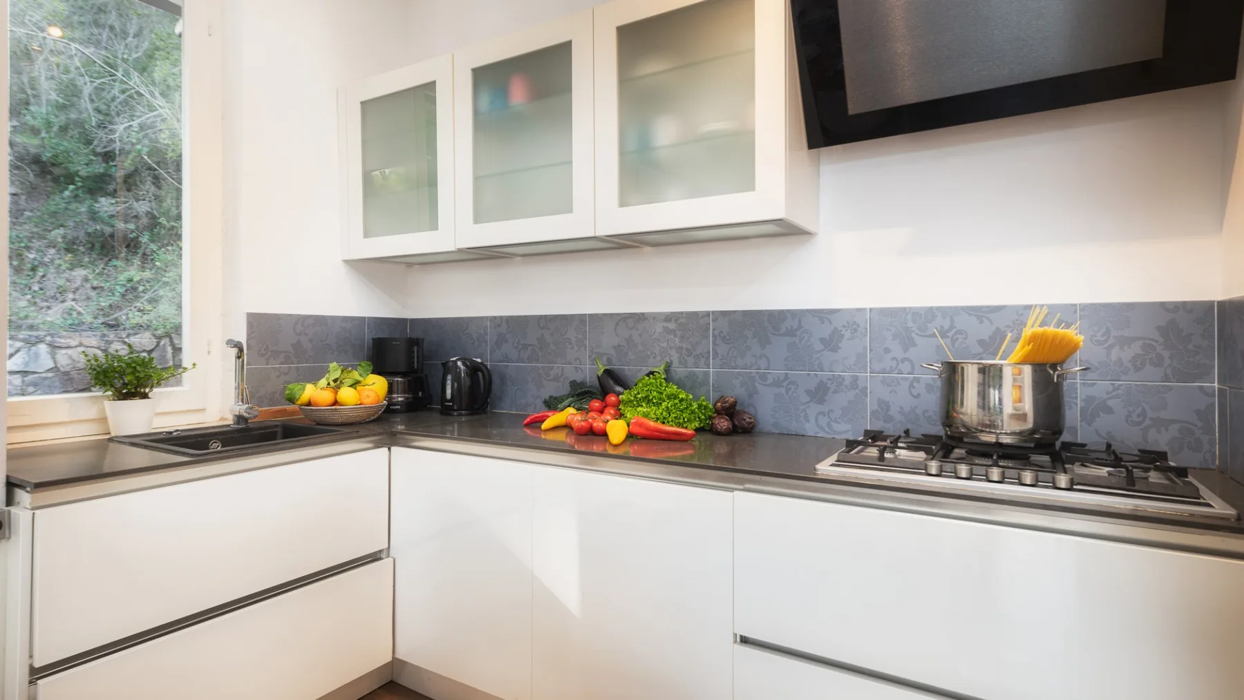 Una cocina moderna y luminosa con armarios blancos y una estufa sobre la encimera.