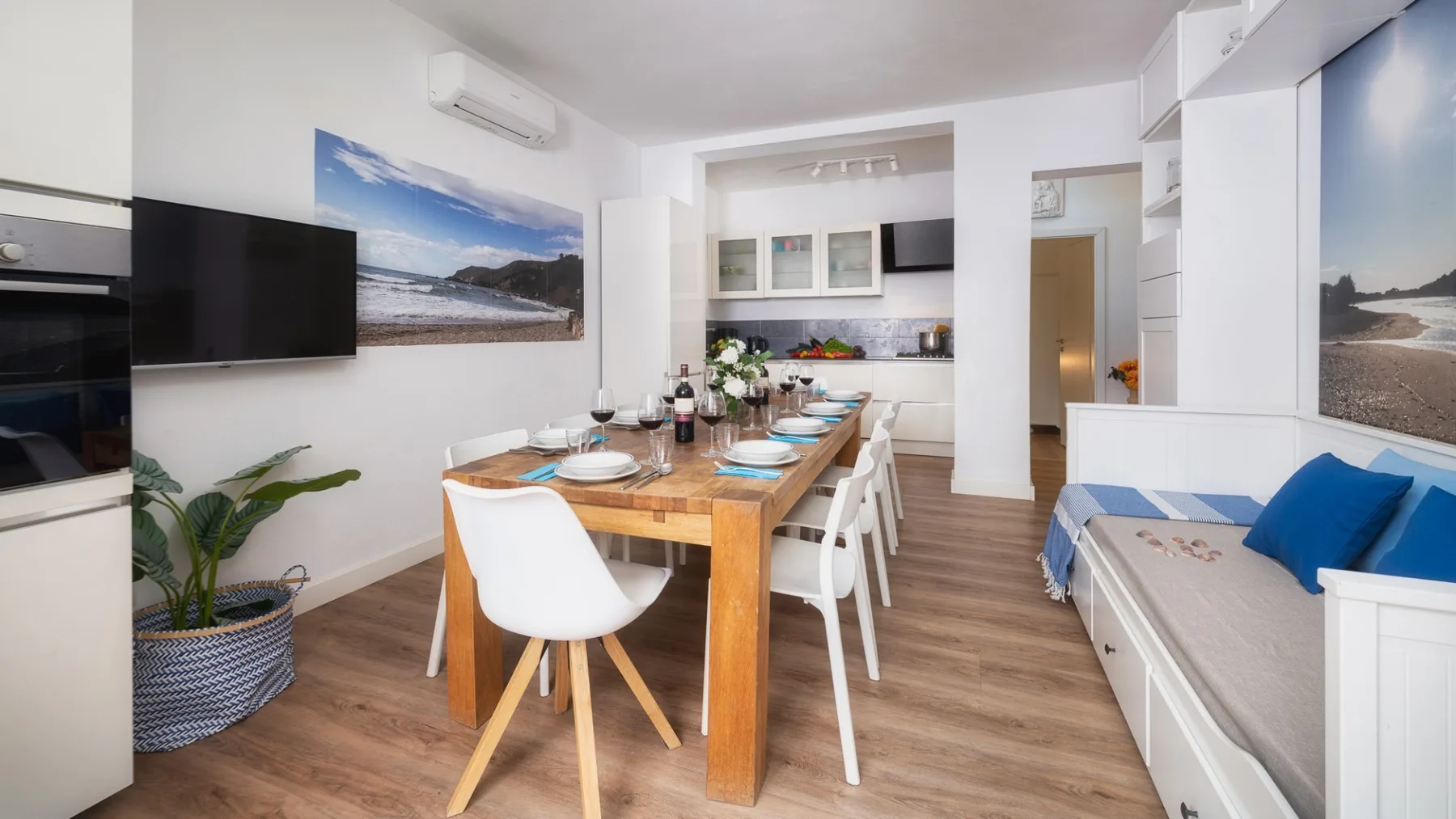 Comedor con mesa de madera y asientos blancos junto a un banco empotrado.
