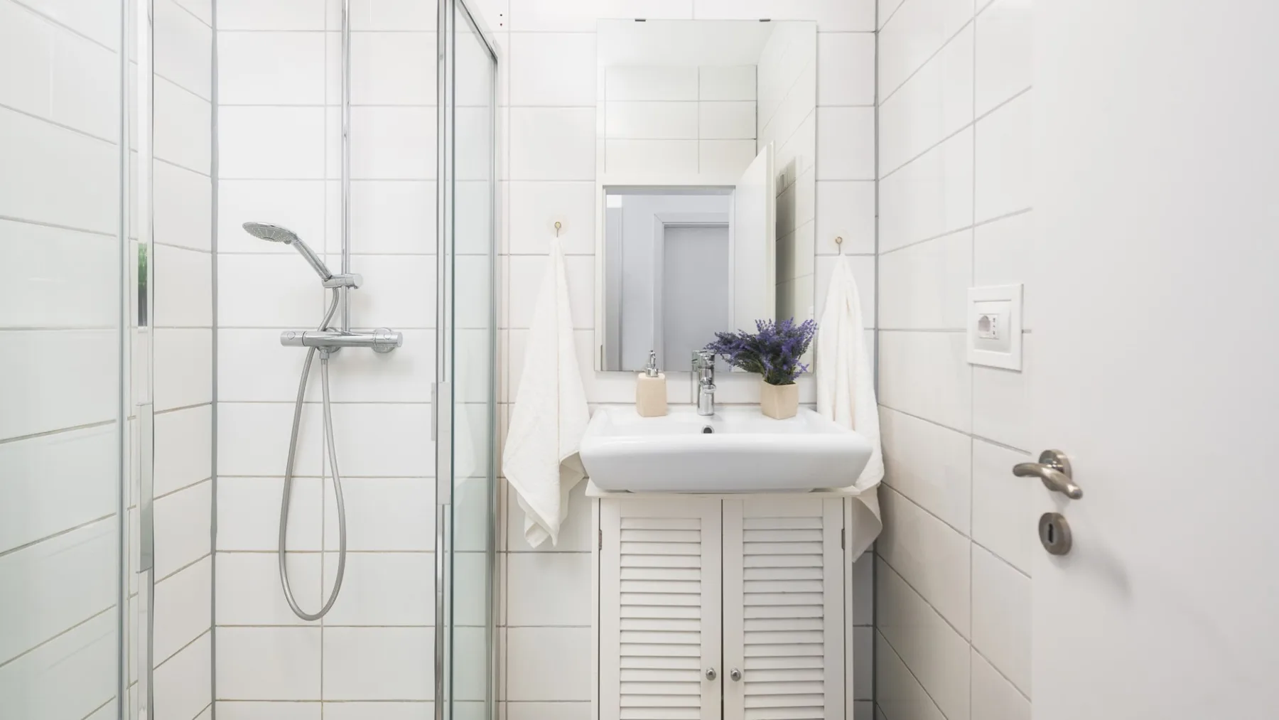 Un baño alicatado con ducha, lavabo y armario con espejo.