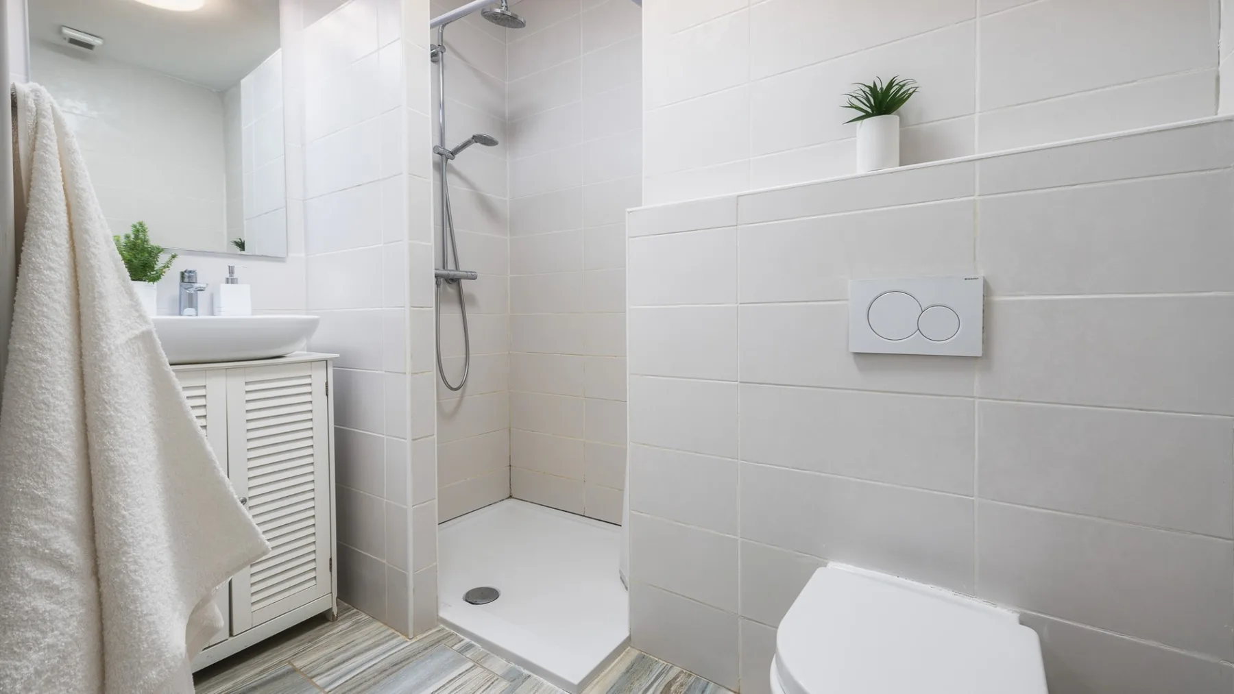 Un baño luminoso con azulejos, ducha, lavabo e inodoro.