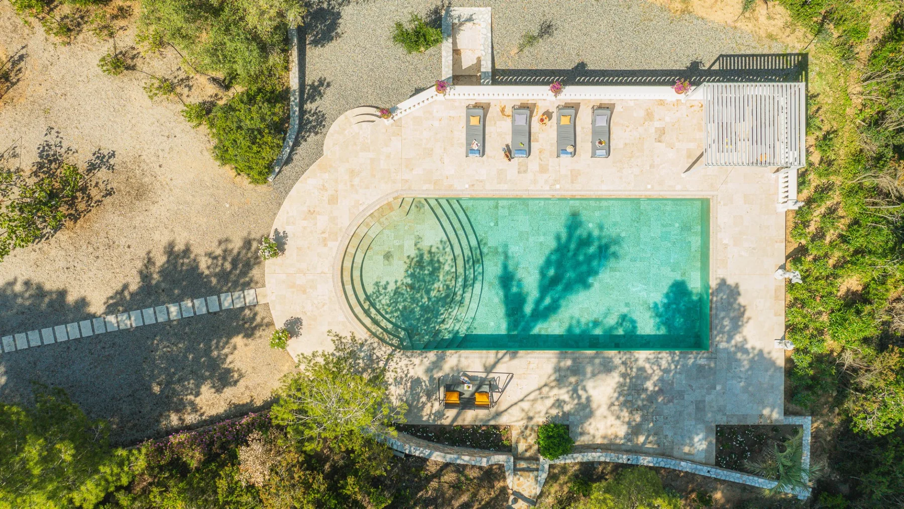 Vista aérea de una piscina al aire libre junto a un patio pavimentado.