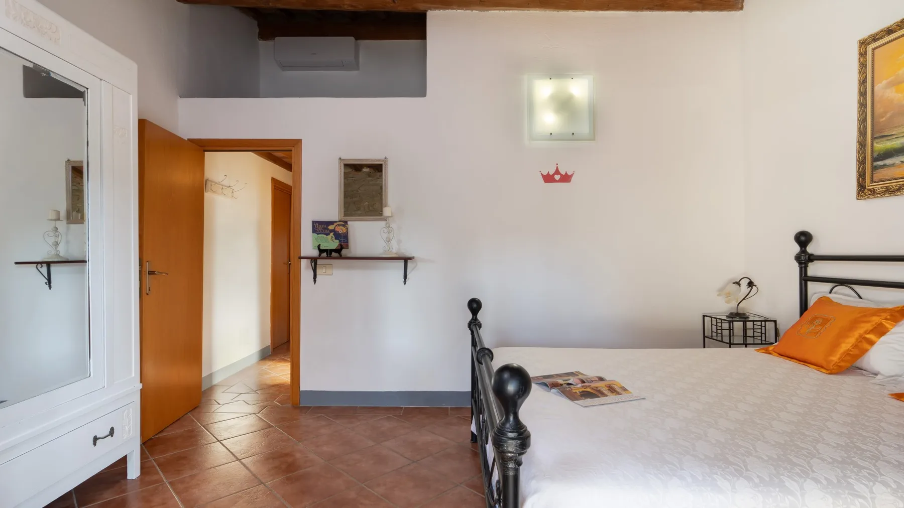 A bedroom with a bed, an open doorway, and a wall-mounted shelf.