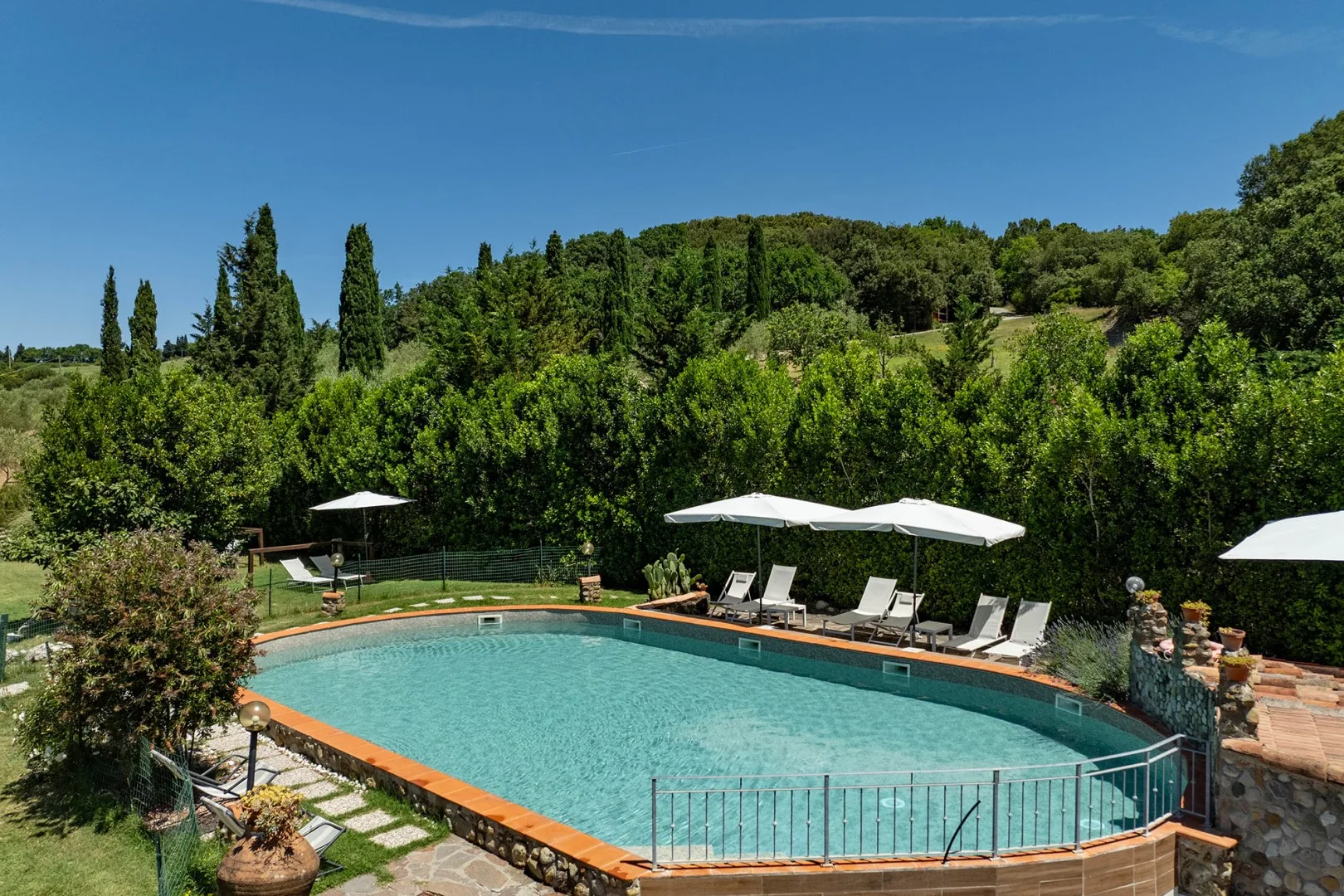An outdoor swimming pool surrounded by greenery and lounge seating.