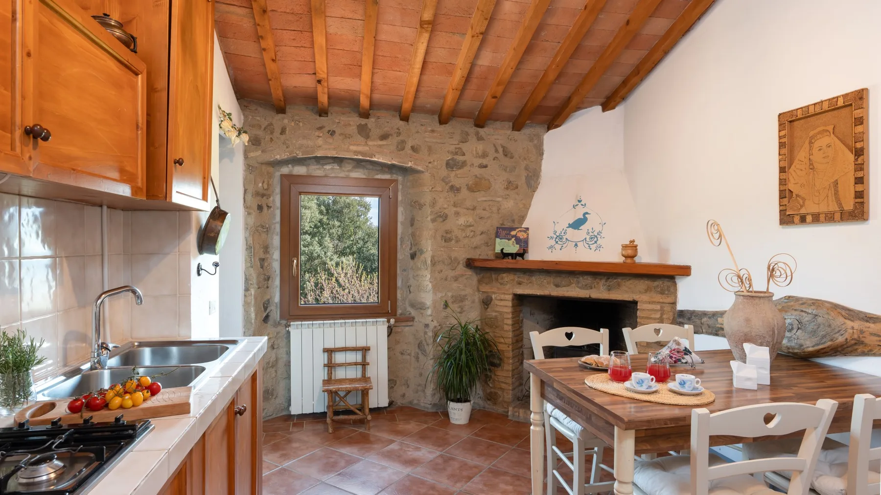 A rustic kitchen and dining area with a stone fireplace and wooden ceiling.
