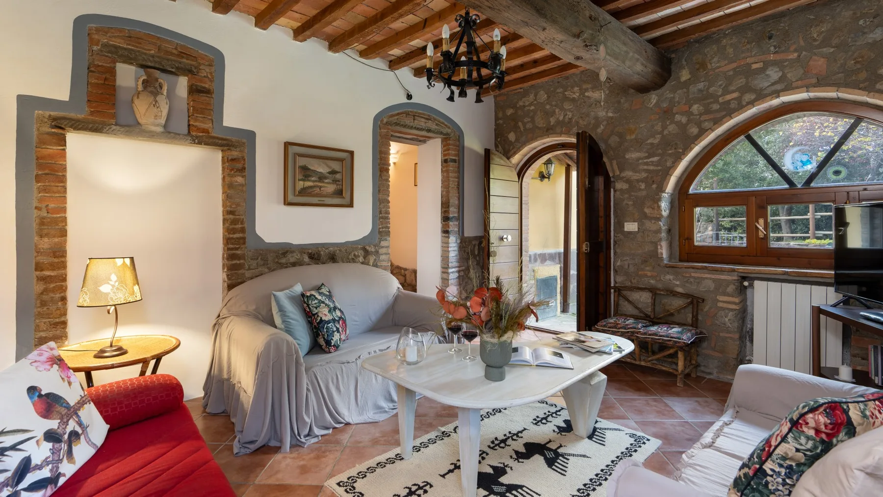 A rustic living room with seating, a coffee table, and exposed wooden beams.