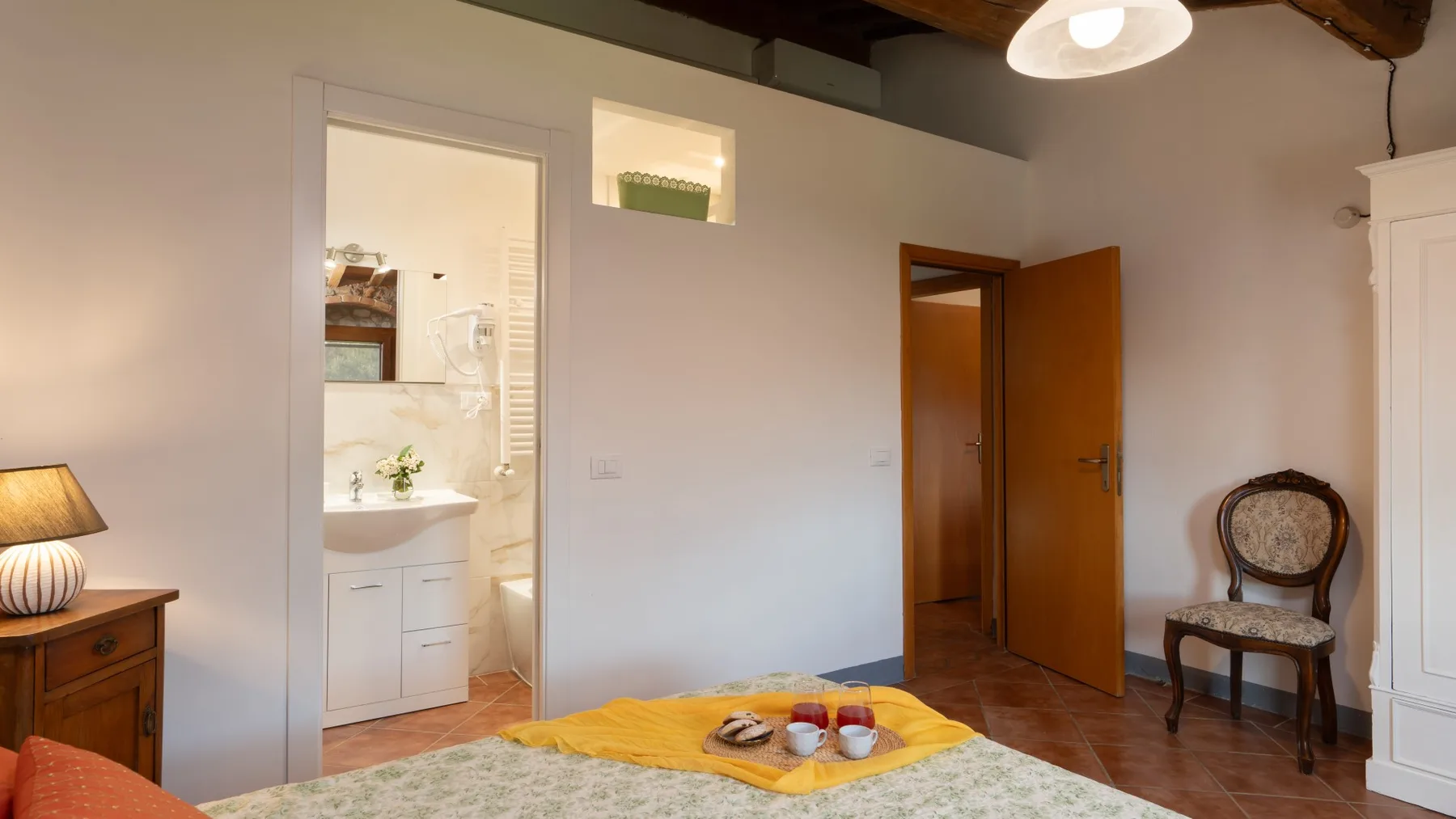 A bedroom with a bed, bedside table, and open doorway to a bathroom.