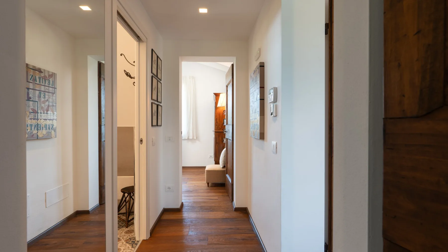 A bright hallway with wood flooring leads to a sitting area.
