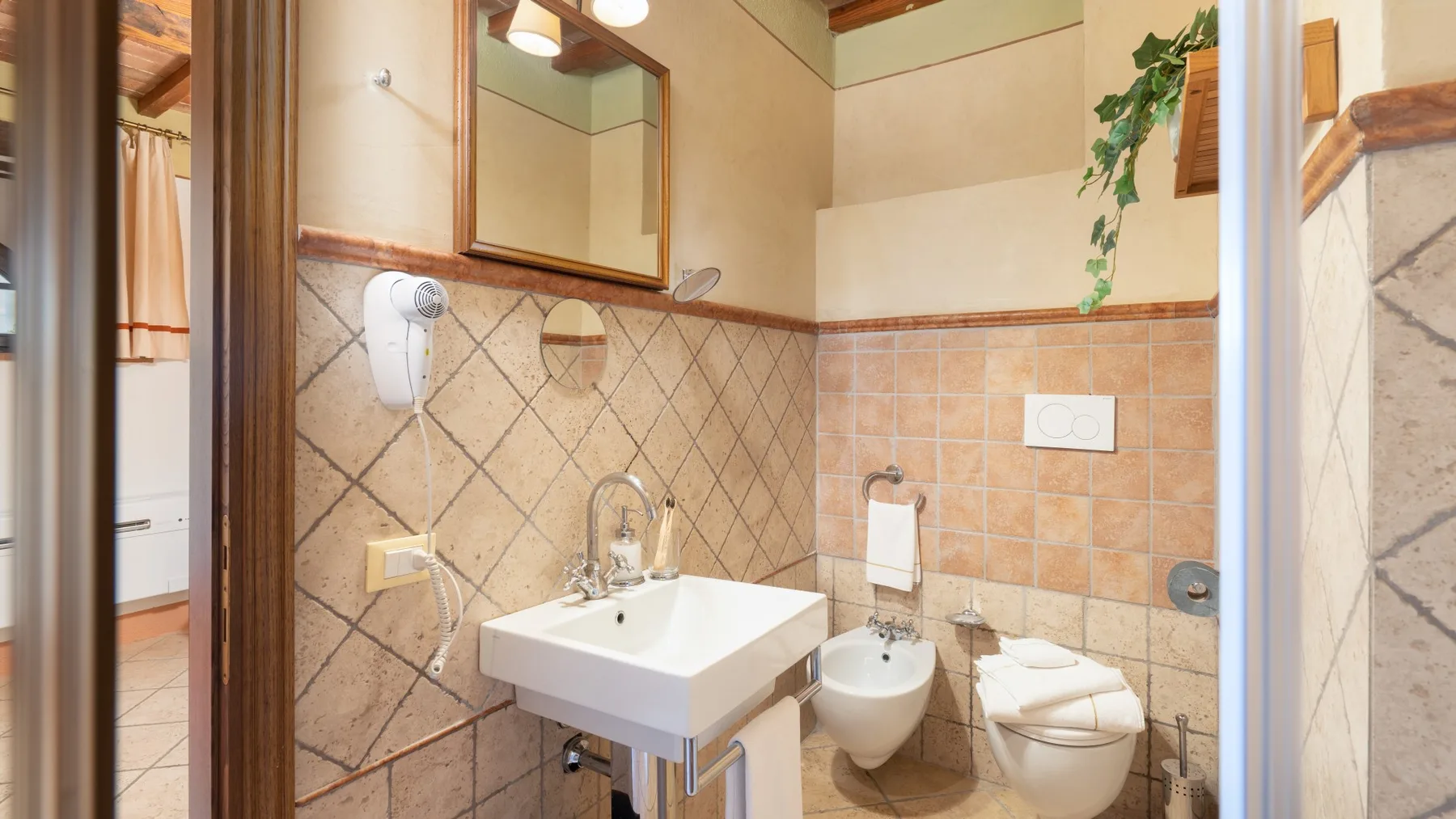 Un baño alicatado con lavabo, espejo e inodoro.