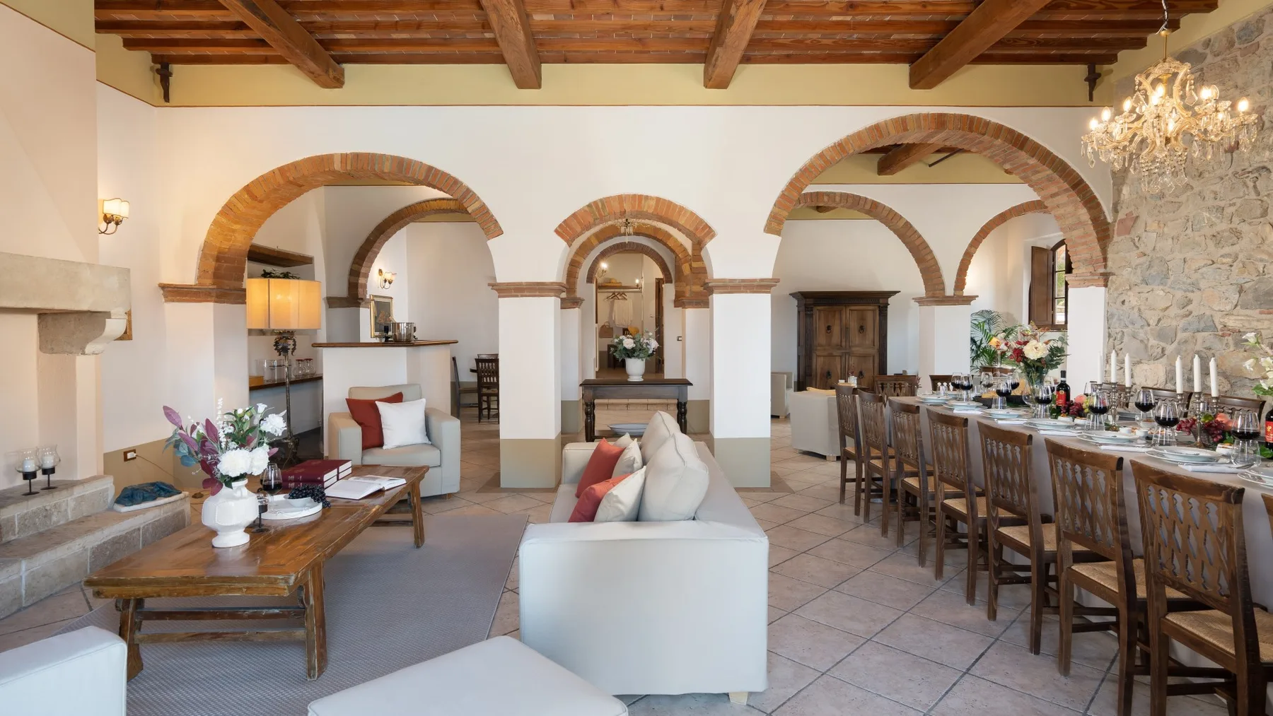 Una amplia sala de estar y comedor con arcos y una larga mesa de comedor.