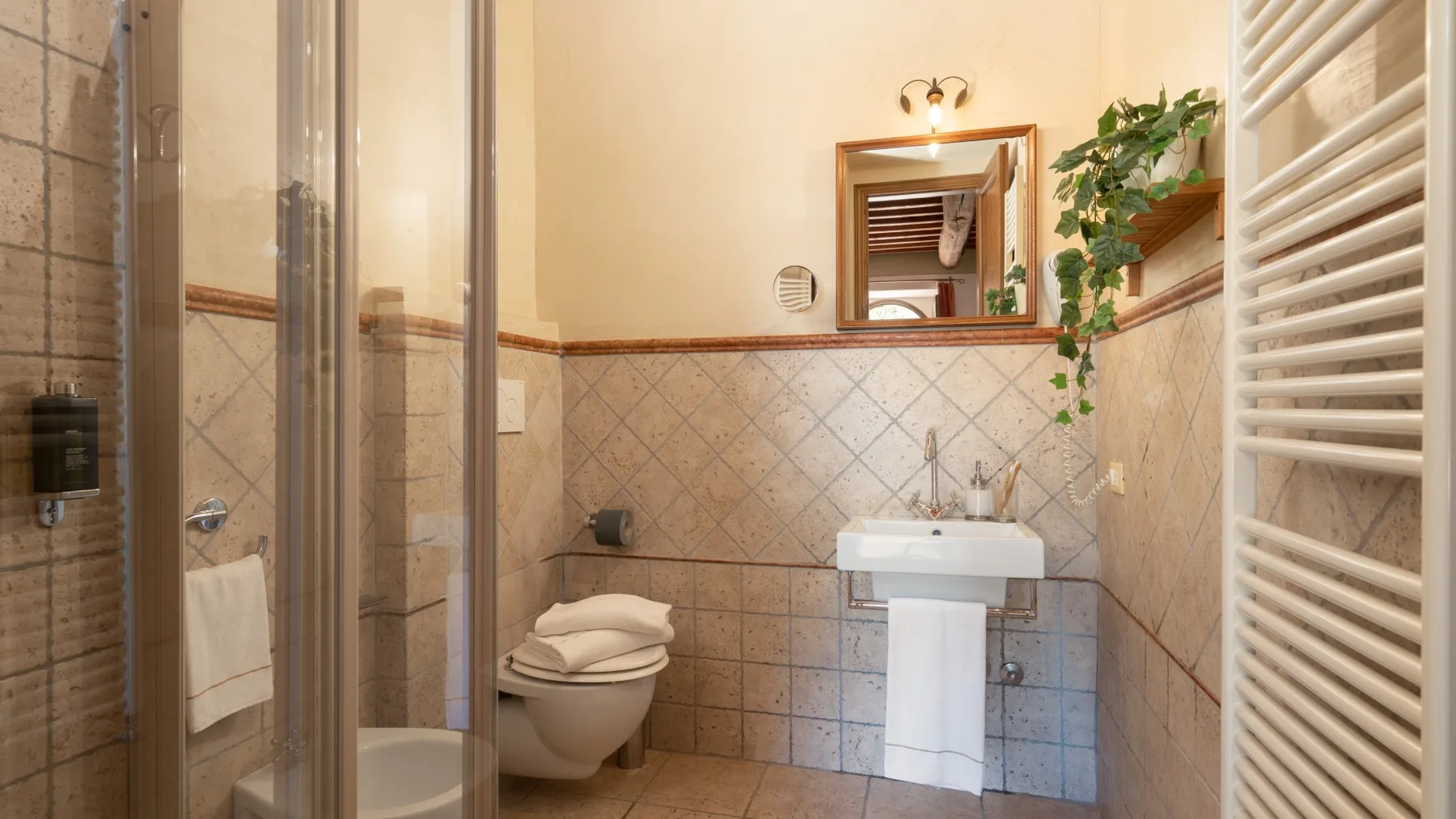 Un baño con azulejos, ducha, inodoro y lavabo suspendido.