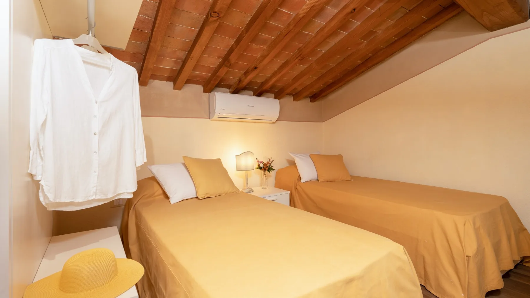 Un dormitorio con dos camas, lámparas de noche y batas blancas colgadas en la pared.