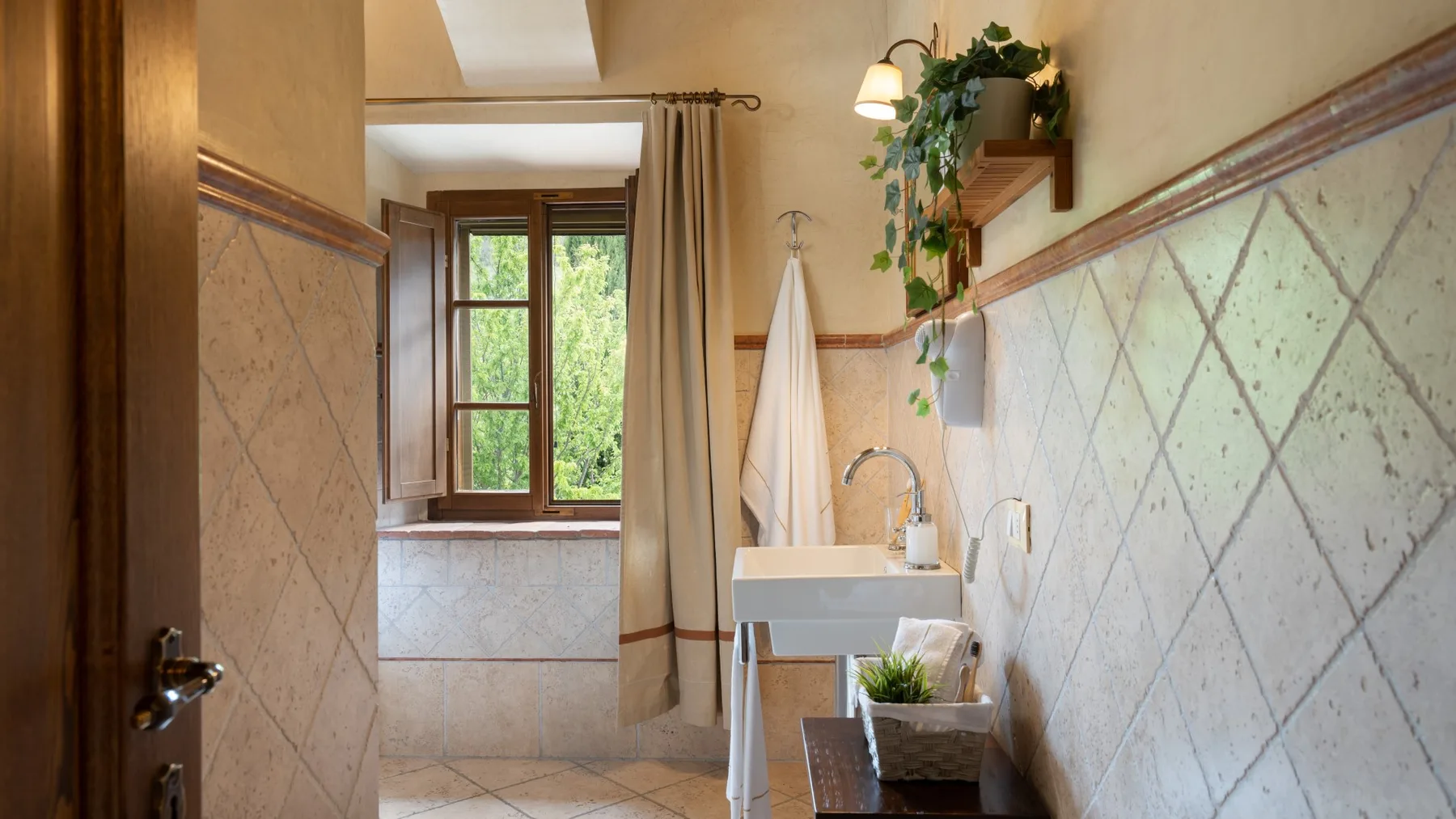 Un baño con azulejos, lavabo, espejo y ventana.