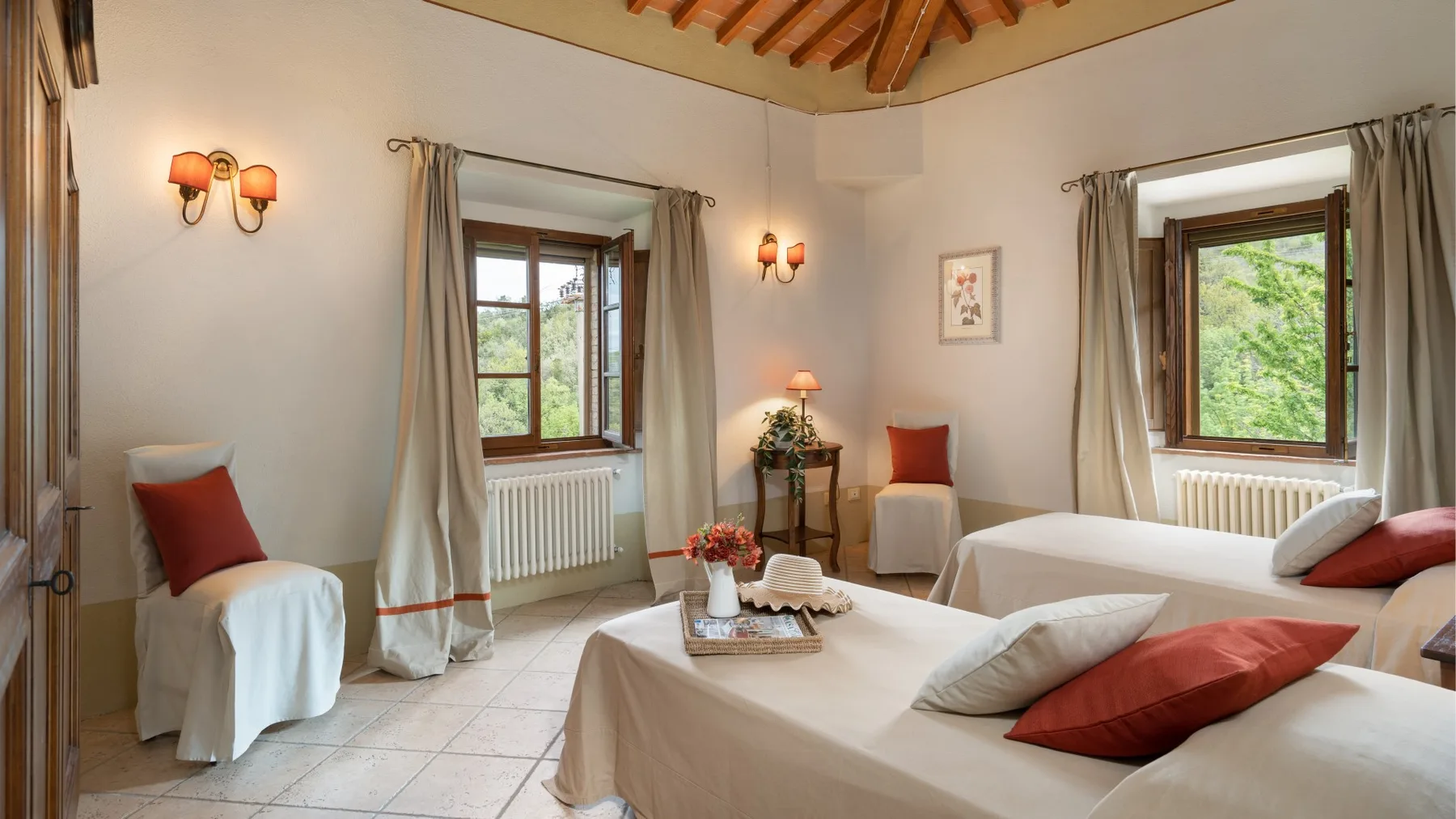 Un dormitorio con una cama, una pequeña zona de estar y ventanas con vistas a la vegetación.