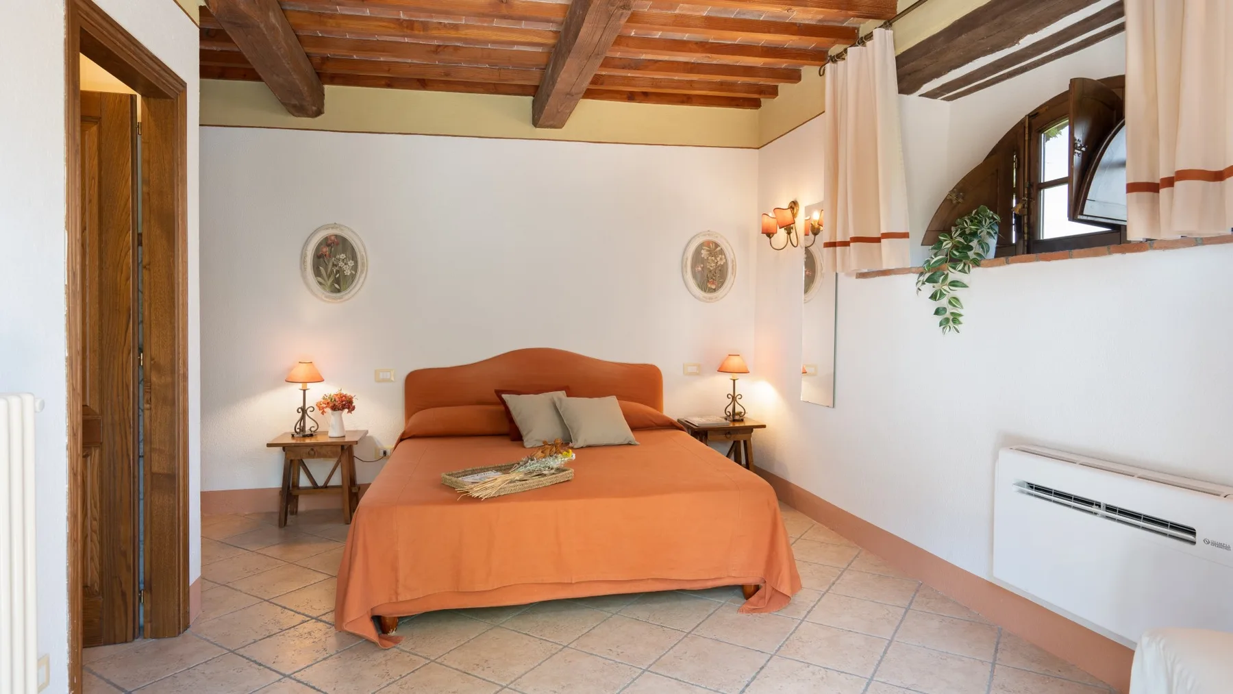 Un dormitorio con una cama naranja y mesitas de noche bajo vigas de madera expuestas.