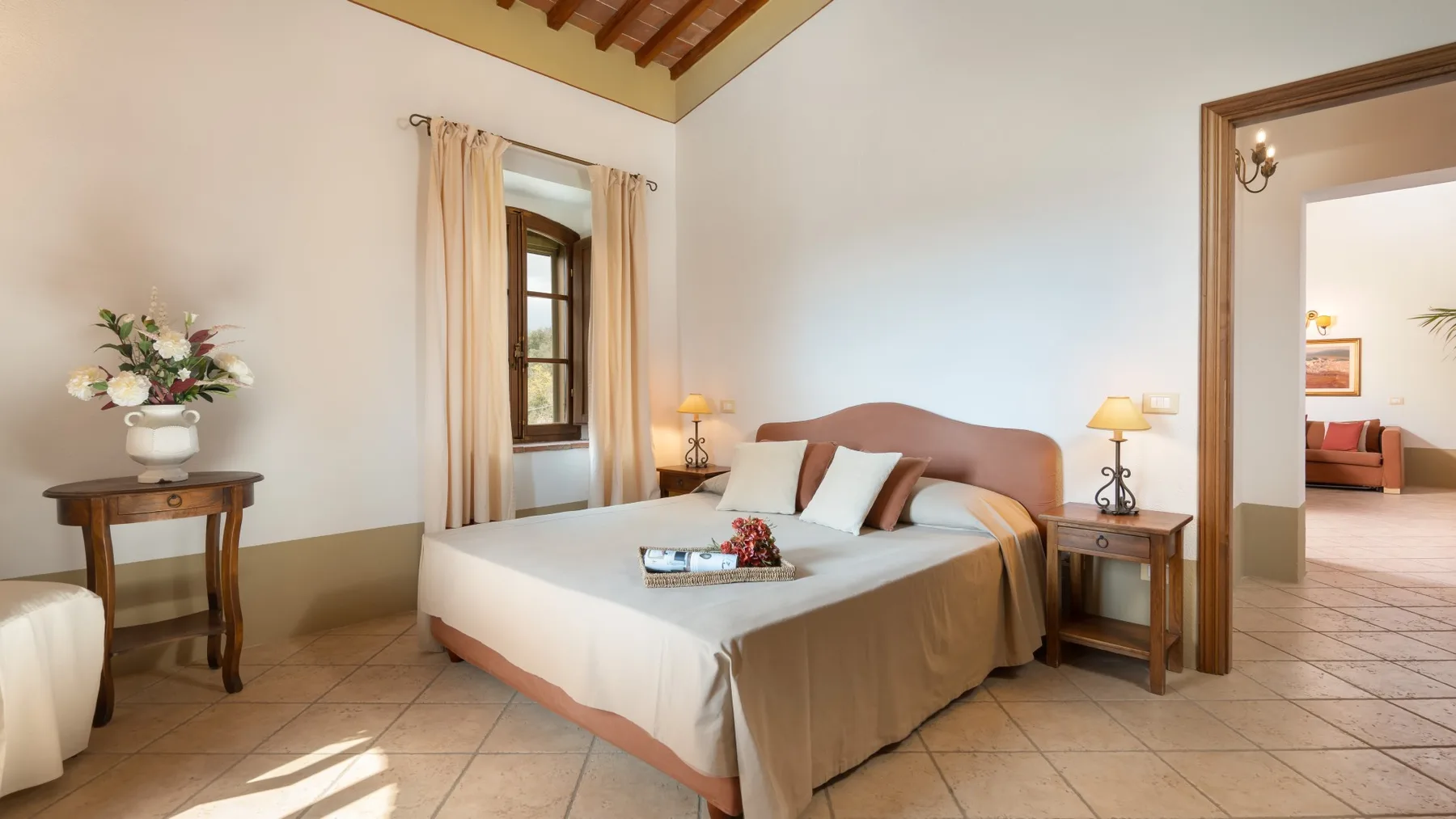 Un dormitorio con cama doble, mesitas de noche y una ventana con cortinas.