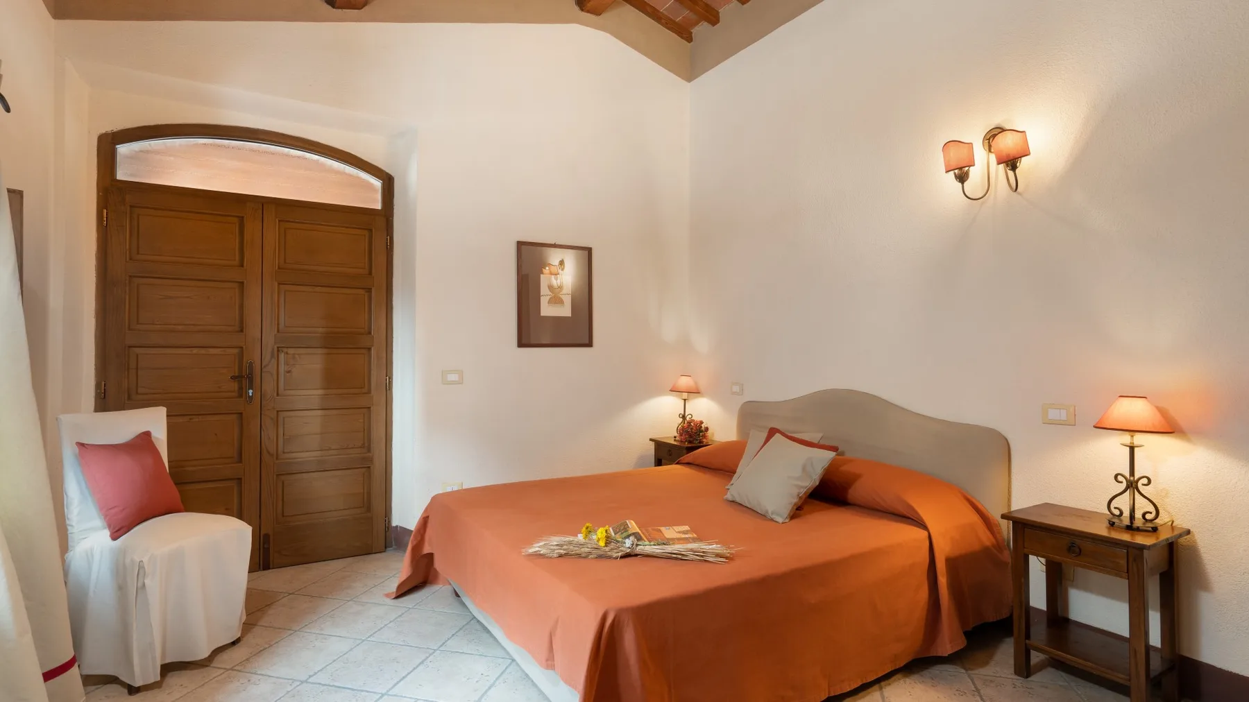 Un dormitorio con una cama grande vestida con ropa de cama naranja y una puerta de madera.