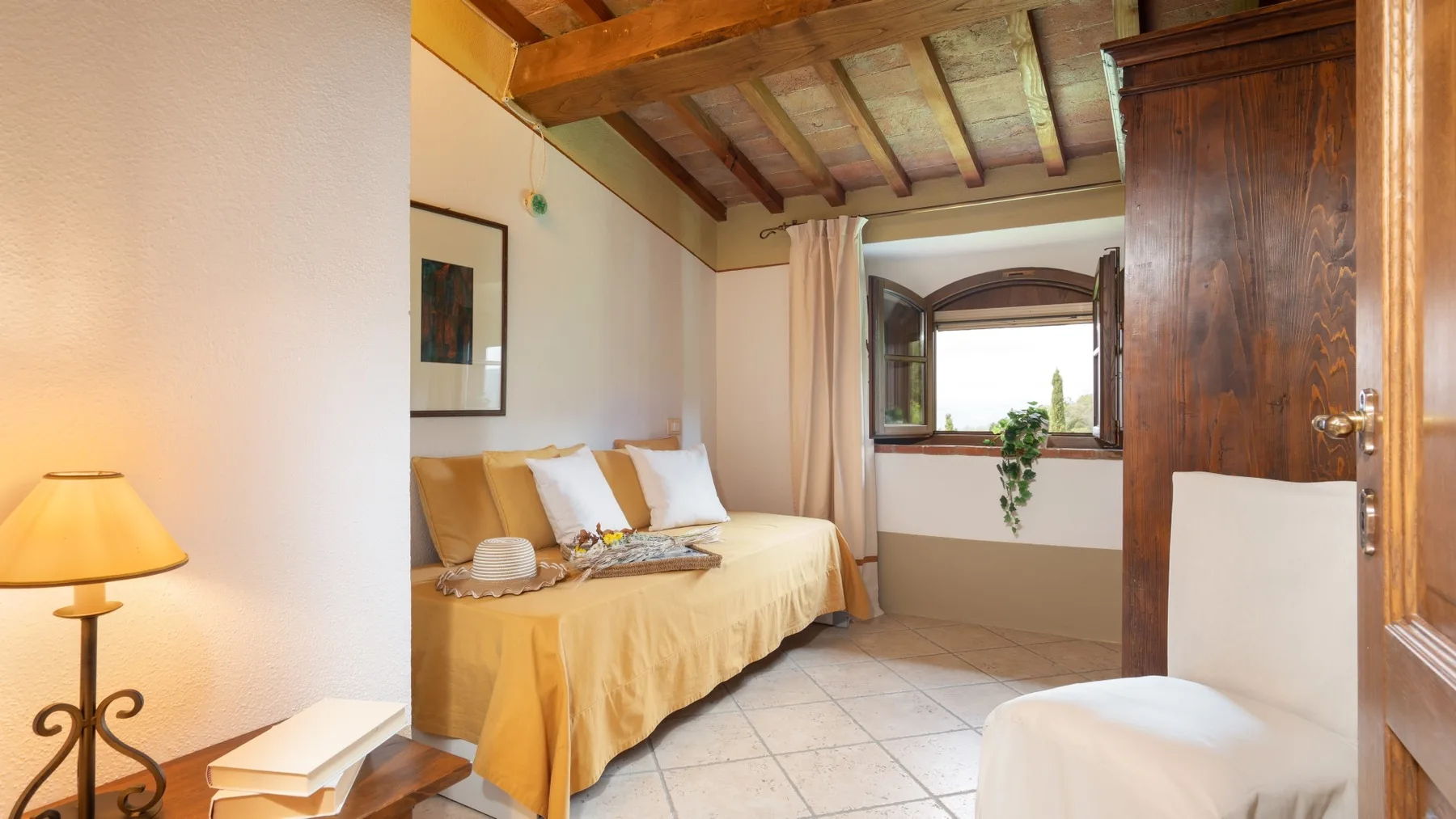 Un dormitorio con una cama bajo vigas de madera vistas y una ventana.