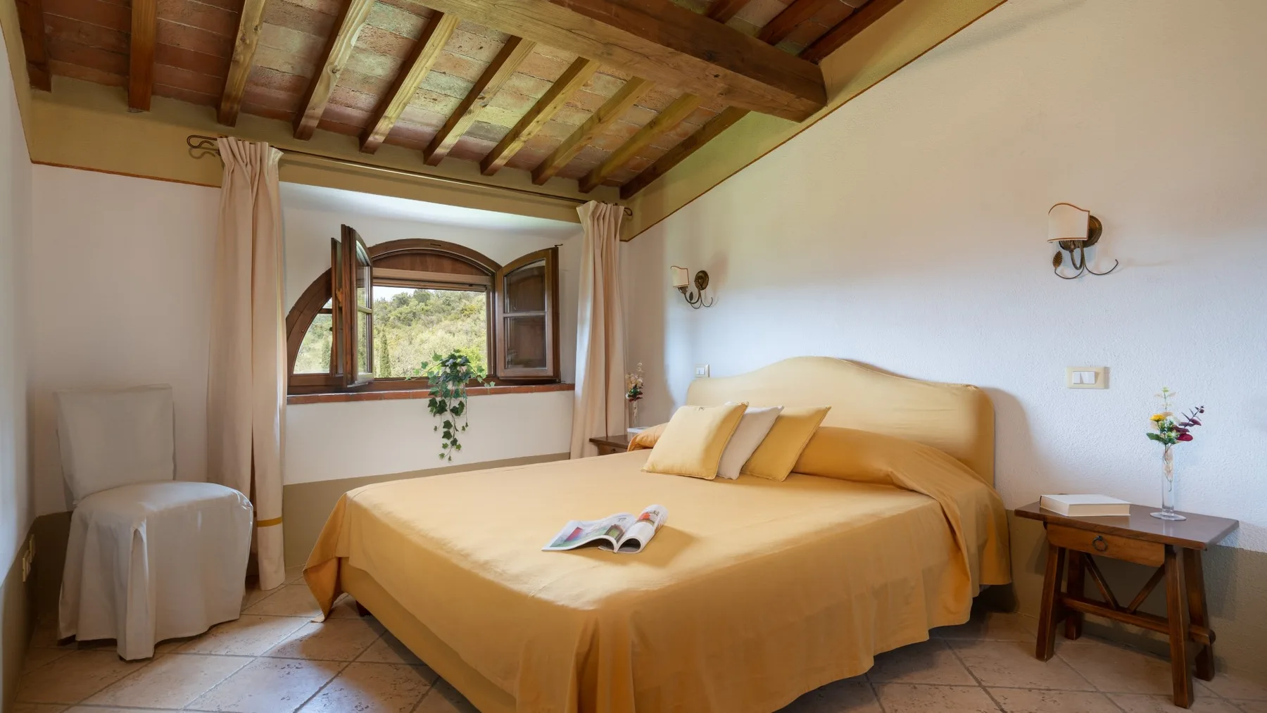 Un dormitorio con una cama grande, una ventana abierta y vigas de madera expuestas.
