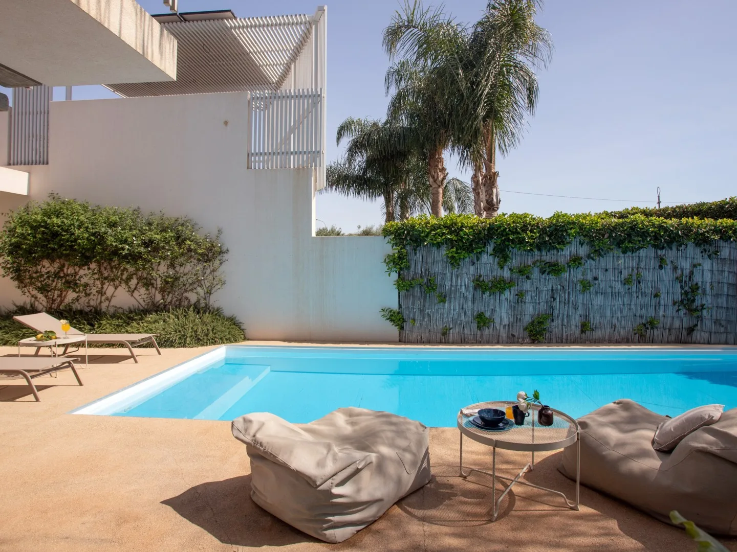 An outdoor swimming pool is surrounded by a paved deck and lounge seating.