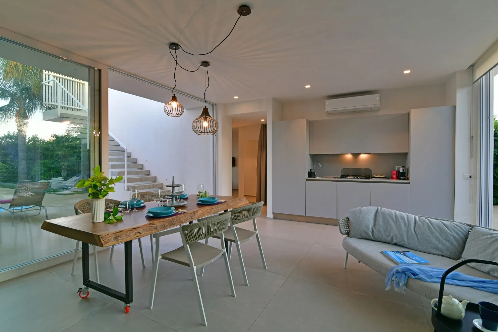 A modern living and dining area with a kitchen and staircase.