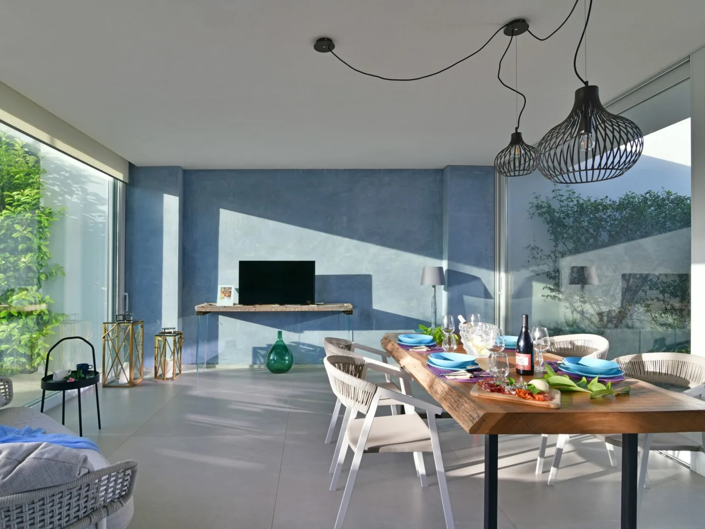 A modern dining area with a wooden table beside large windows.