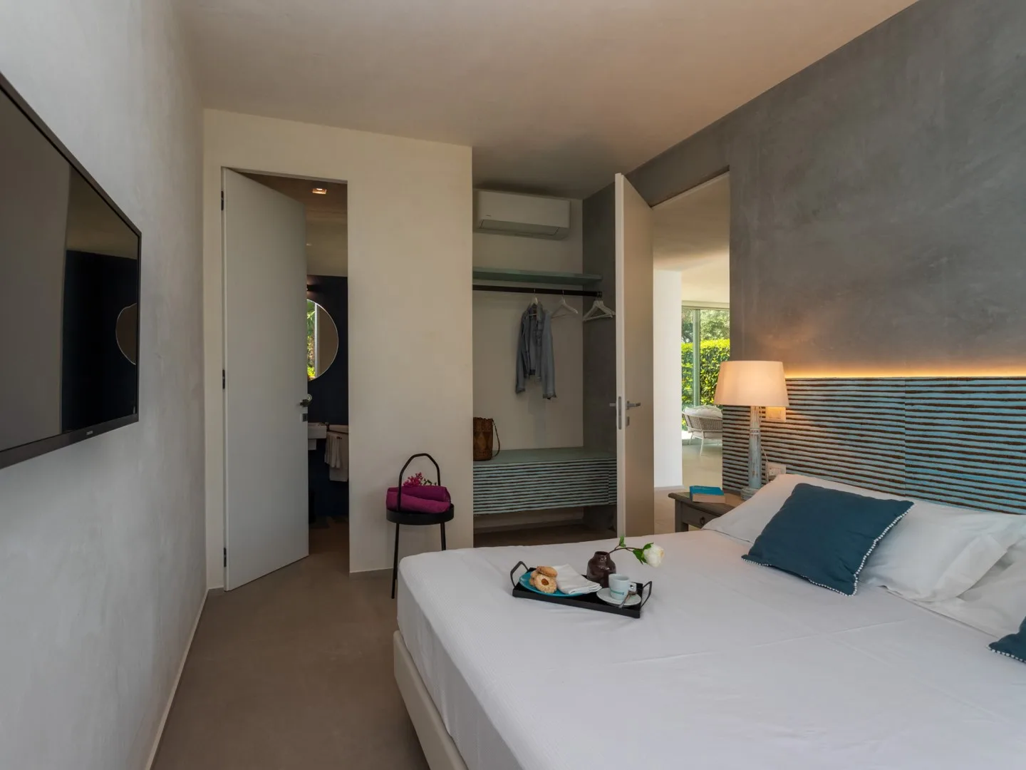 A bedroom with a neatly made bed and an open wardrobe.