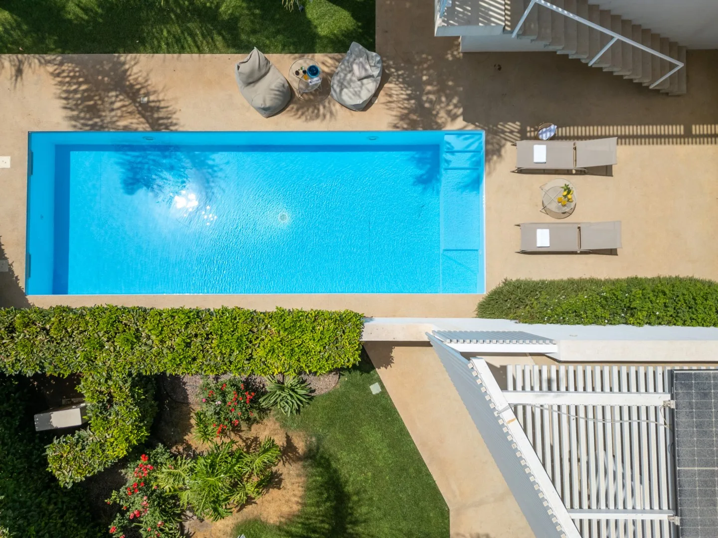 An outdoor swimming pool is surrounded by paved decking and greenery.