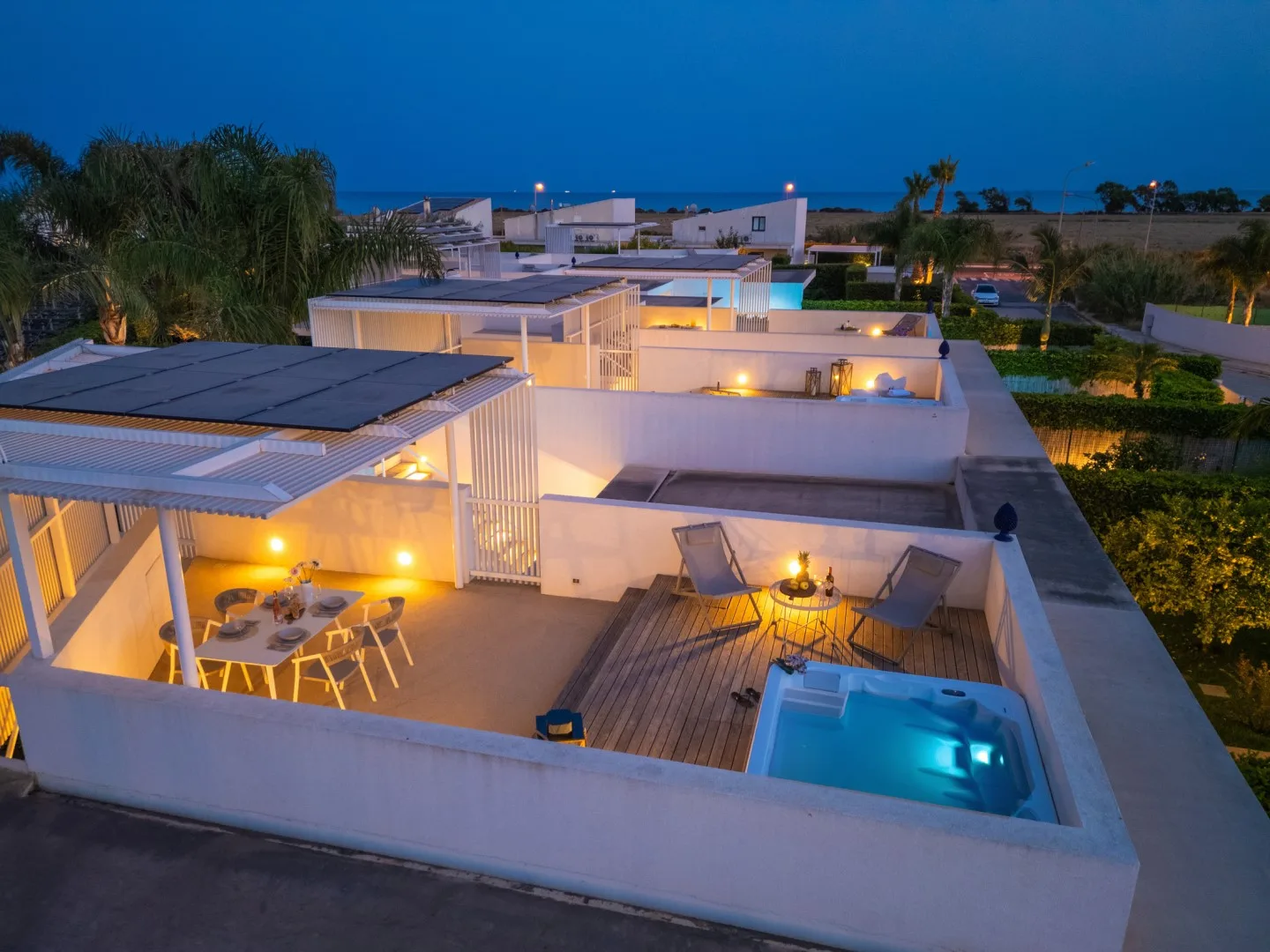 An outdoor terrace at dusk features a dining area and a small pool.