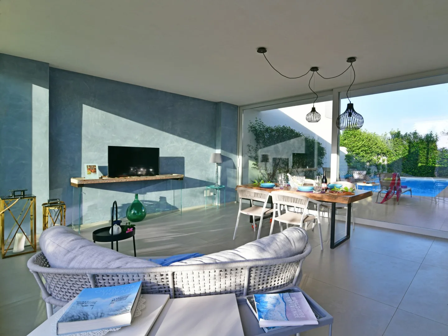 A modern living and dining area opens onto a patio, with a curved seating area and dining table.