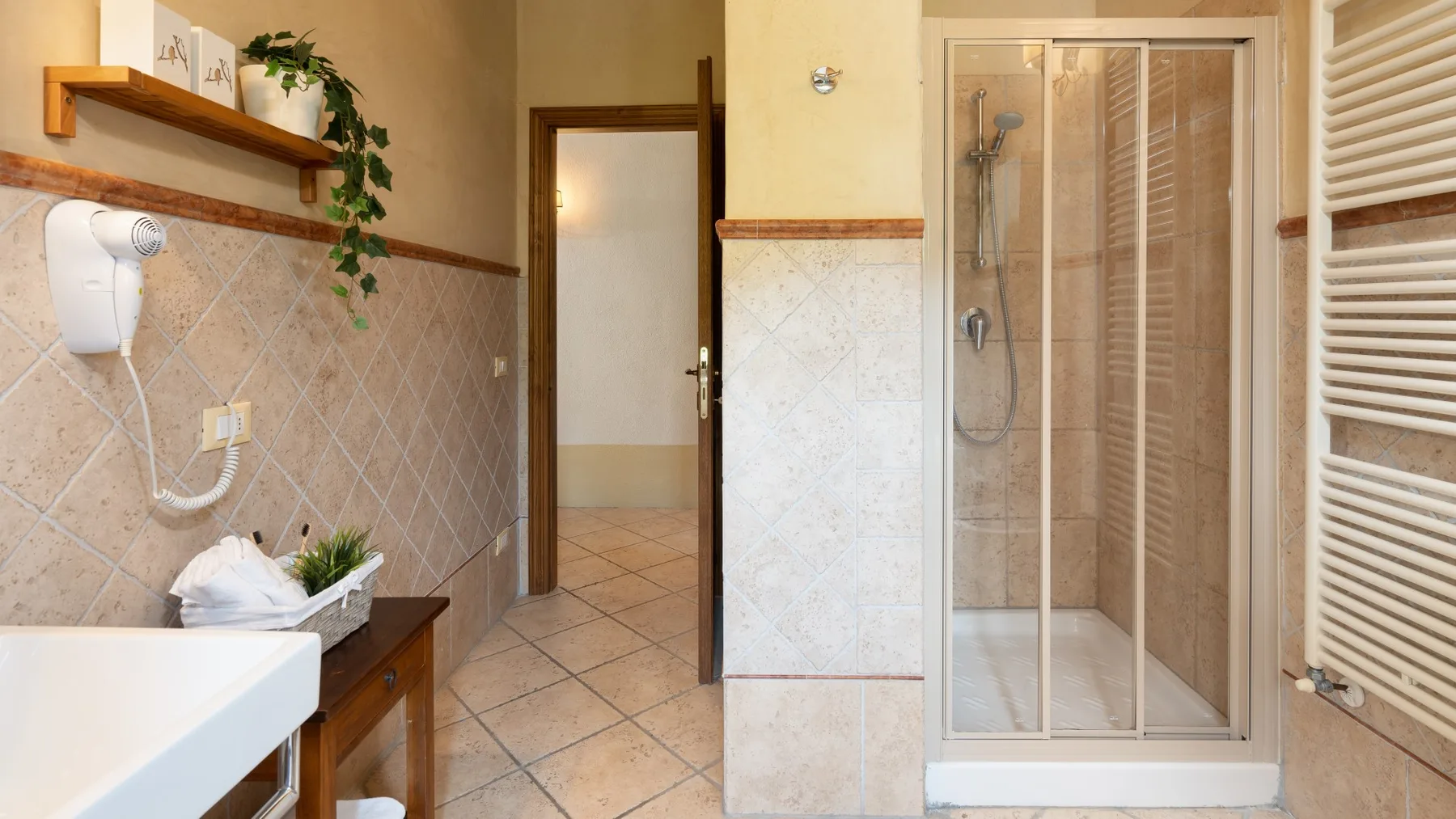 Un baño alicatado con lavabo, ducha y una puerta abierta.