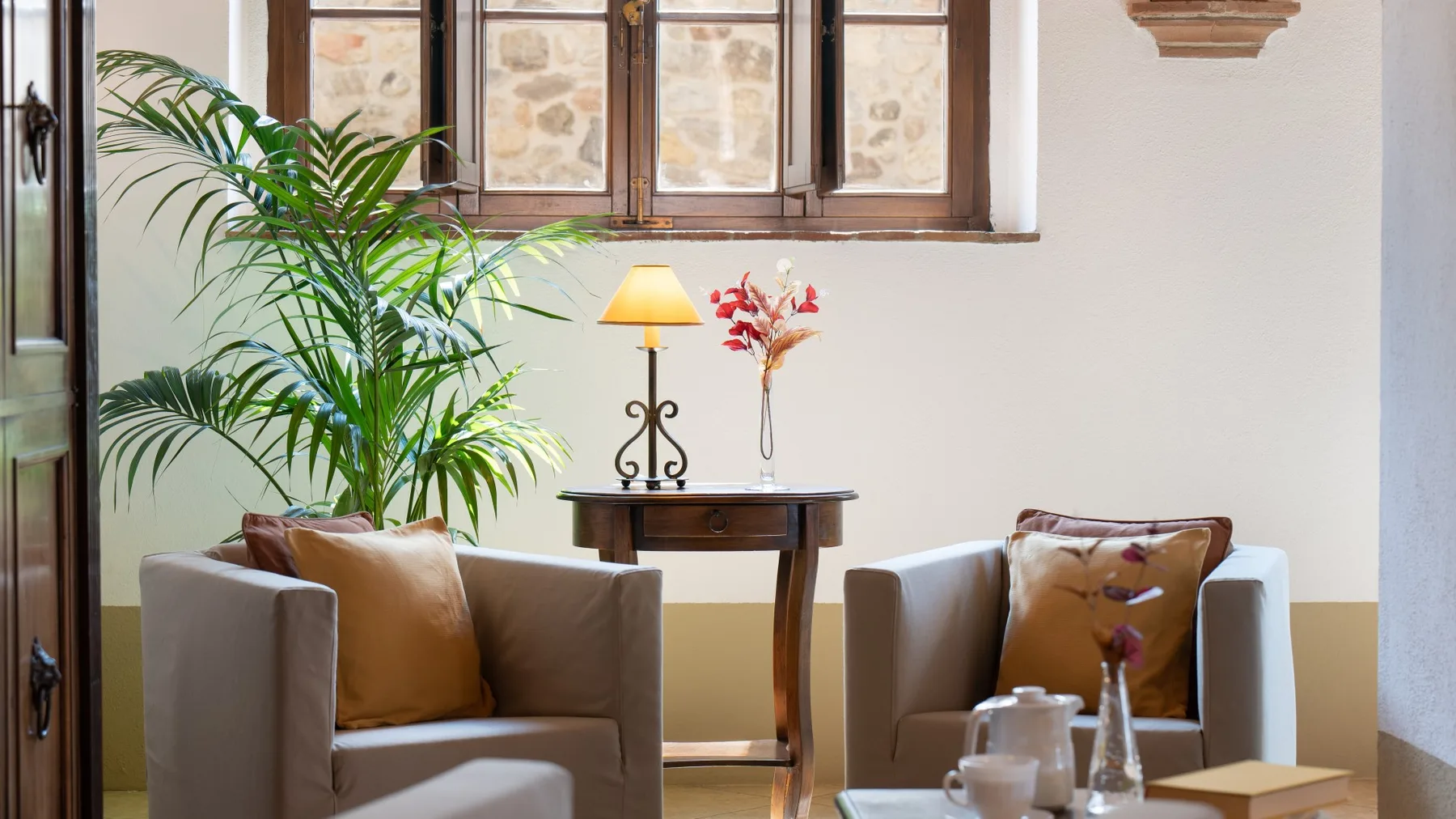 Una zona de estar con dos asientos tapizados, una mesa pequeña y una planta frondosa.