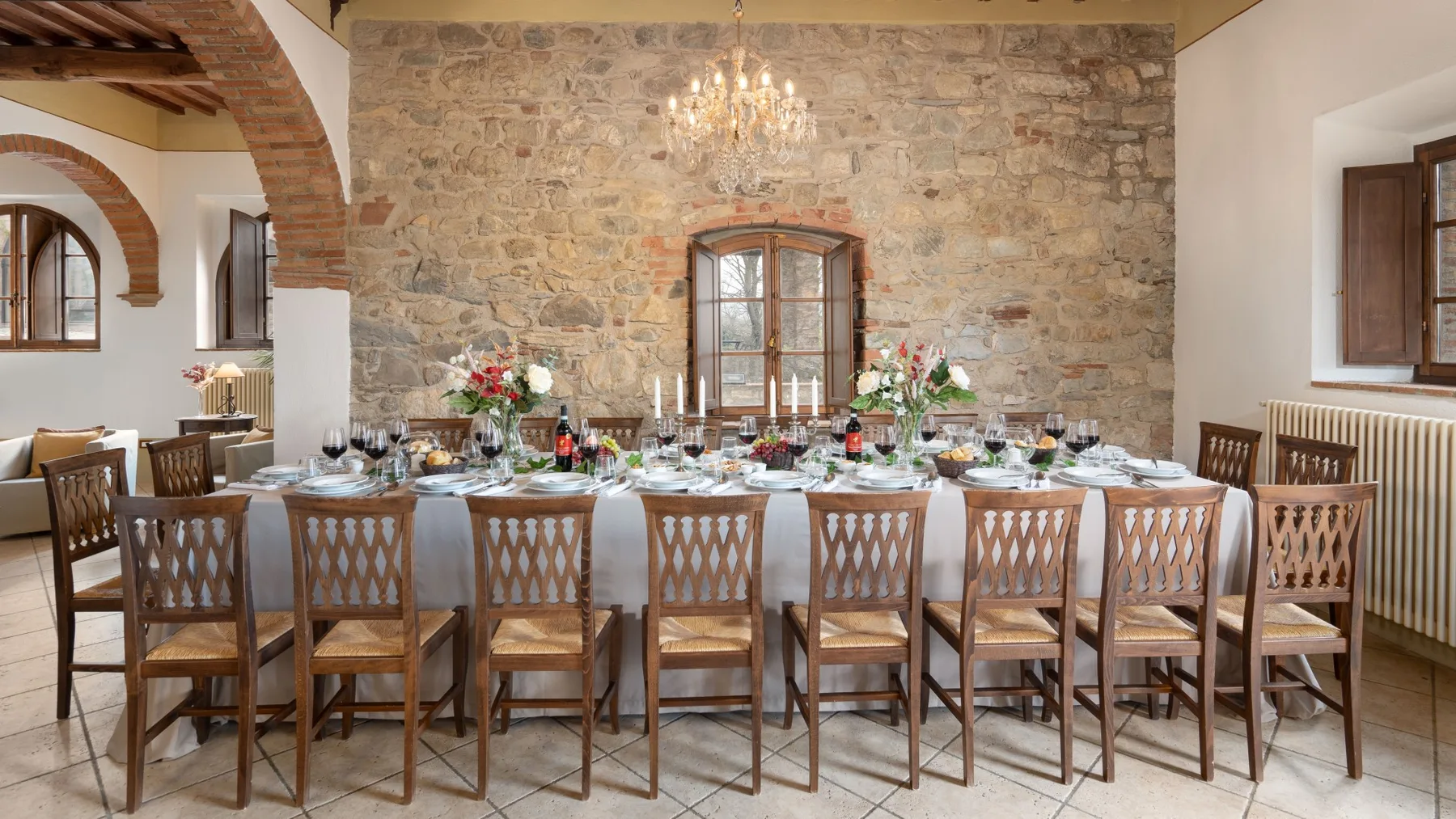 Un comedor con una mesa larga preparada para comer frente a una pared de piedra.