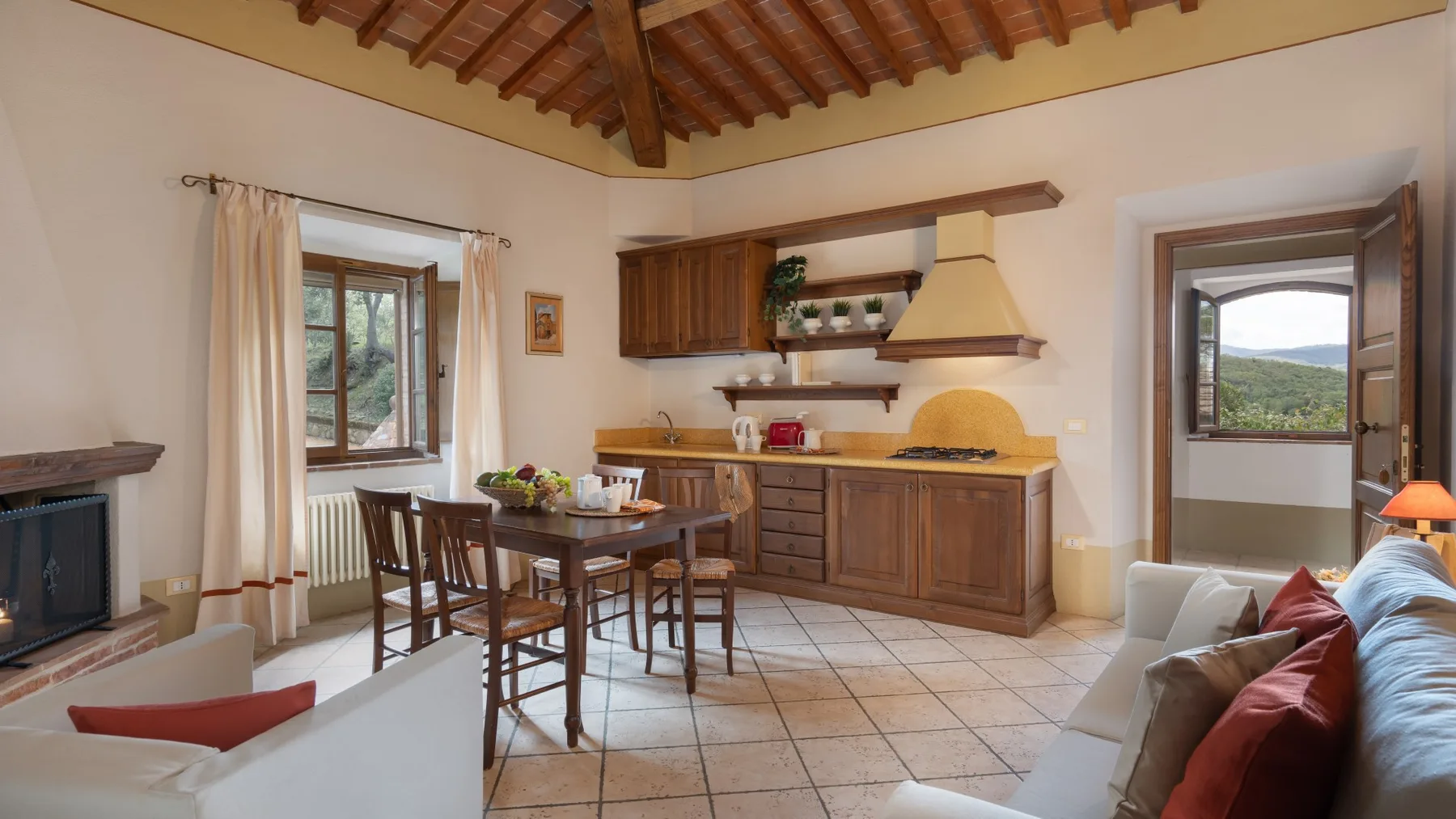 Una sala de estar y comedor con muebles de madera y una vista desde la puerta abierta.