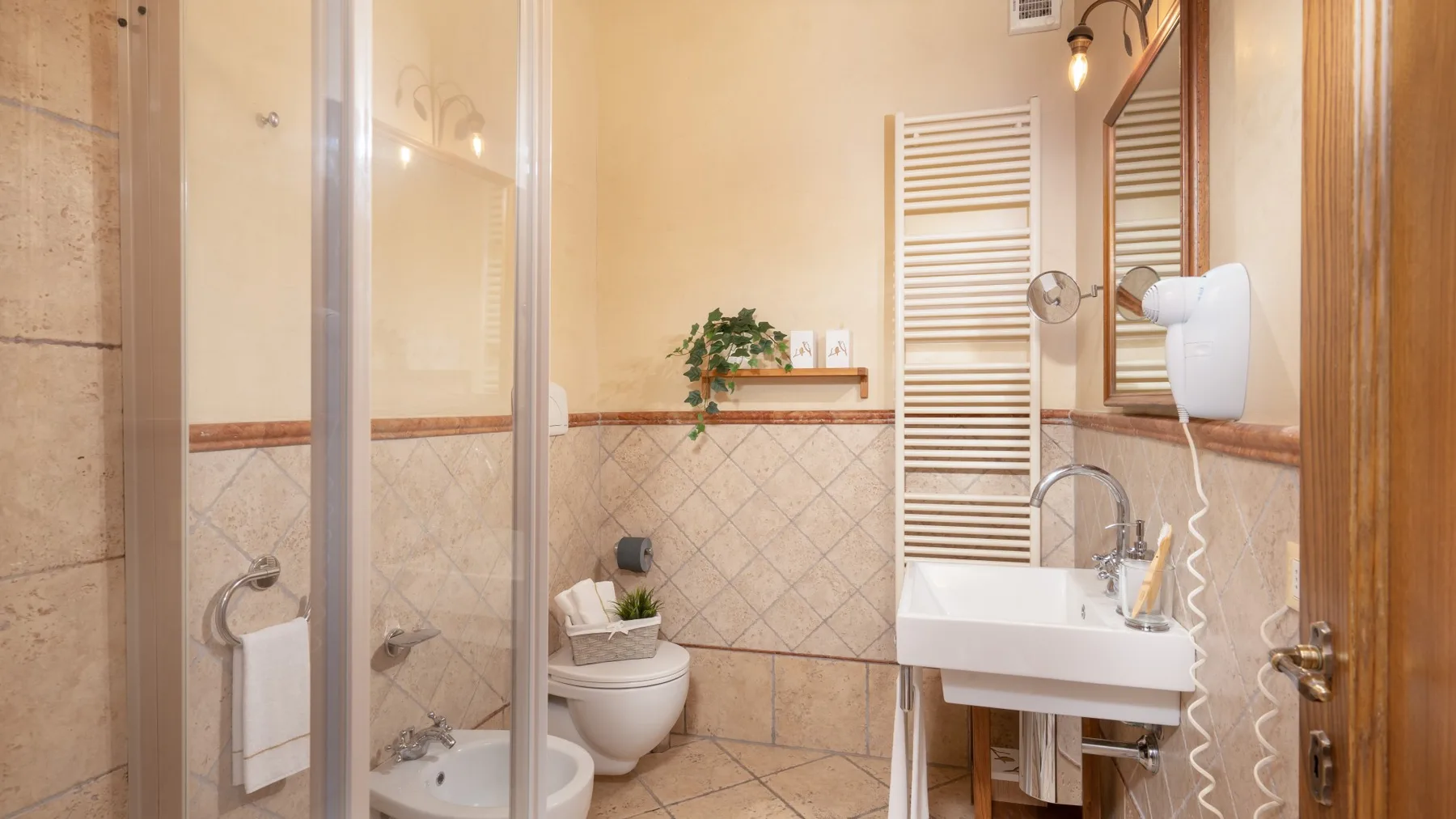 Un baño con ducha, inodoro y lavabo bajo un espejo de pared.