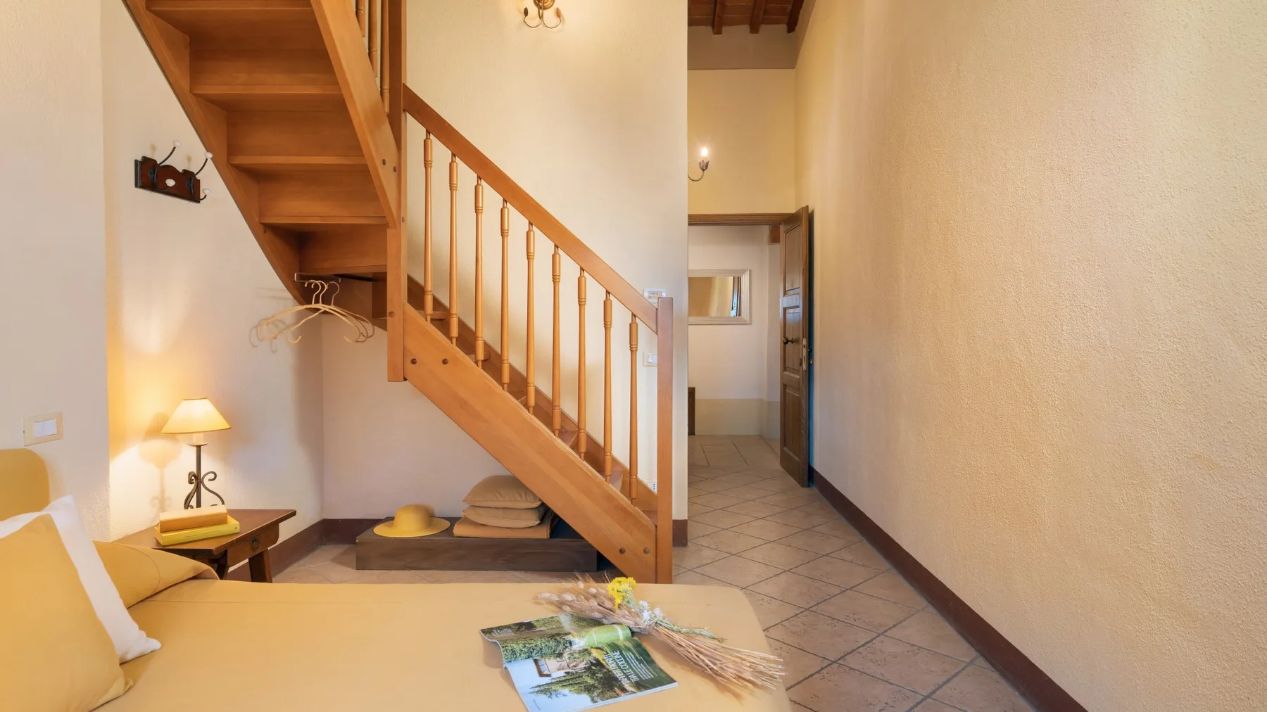Un pasillo interior cálido con una escalera de madera y una pequeña zona de descanso.