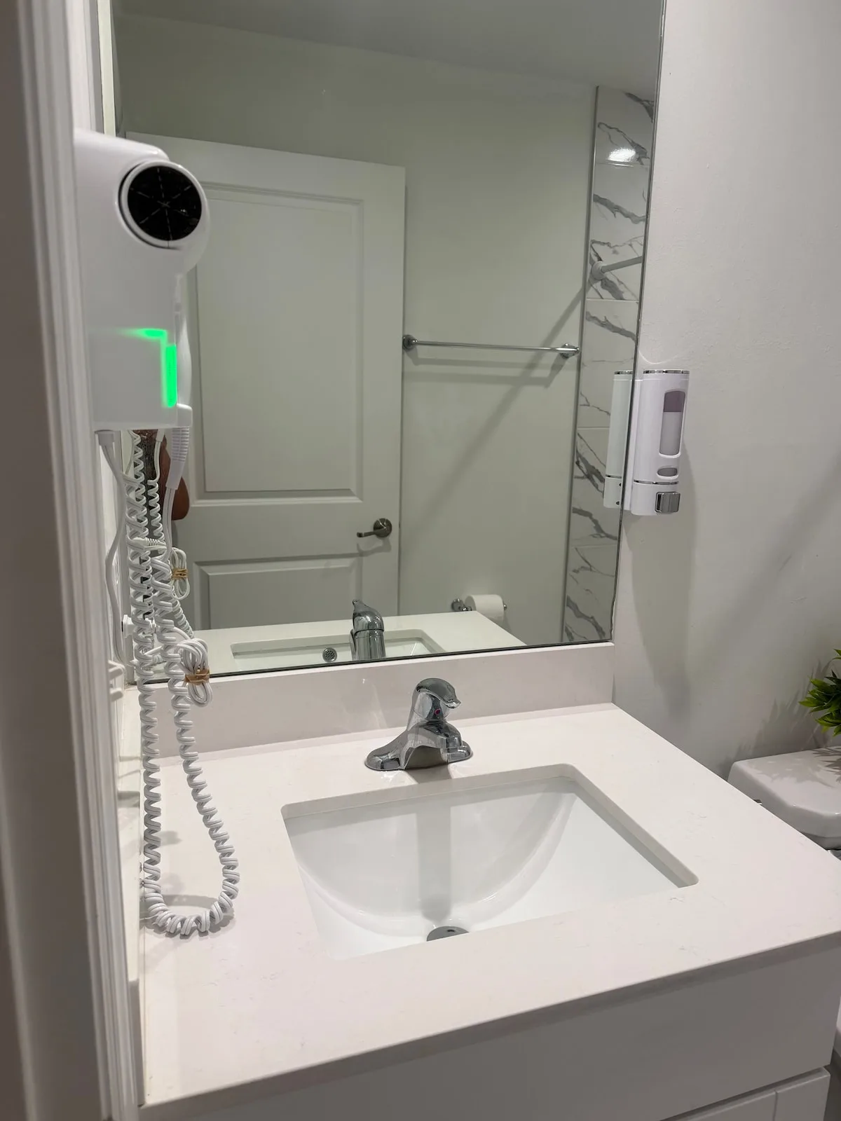 A bathroom vanity with a sink and mirror, with a towel rail visible in the reflection.