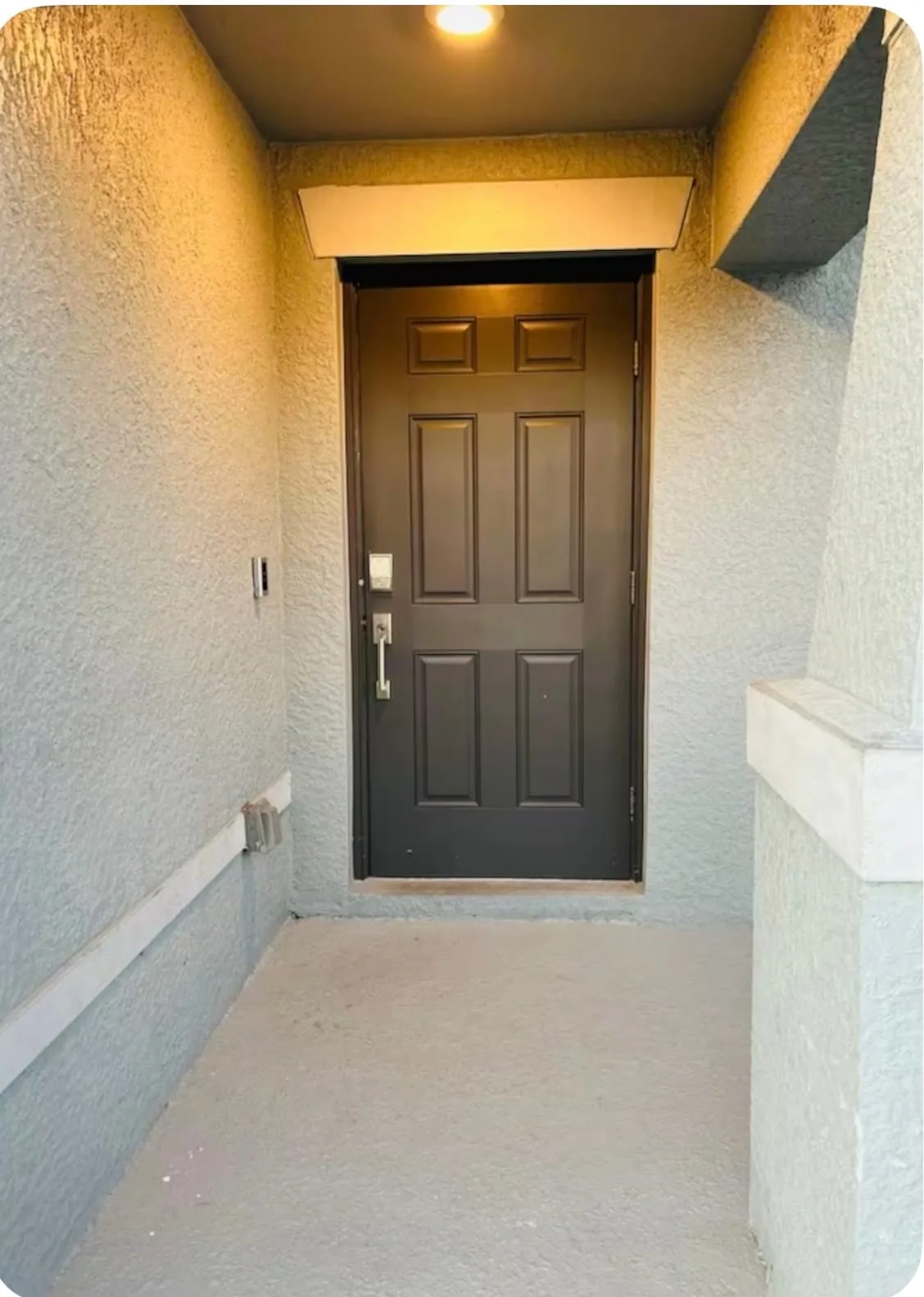 Shared amenity: An exterior entryway with a dark paneled door and light-colored walls.