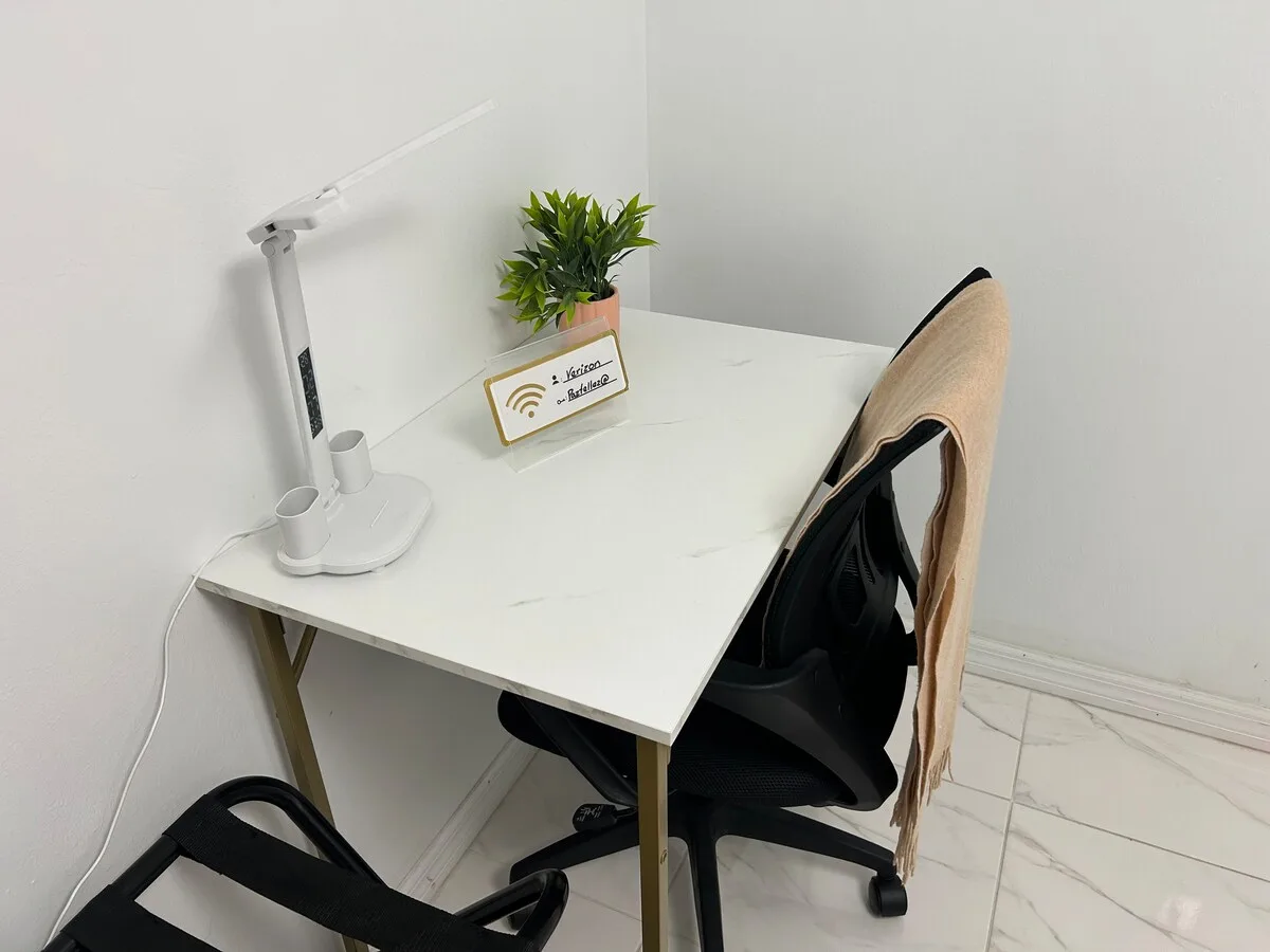A compact desk workspace with a lamp, plant, and chair.